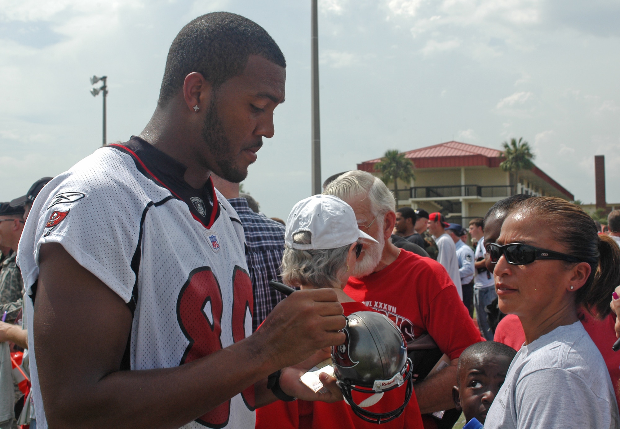 Buccaneers wide receiver Michael Clayton signs a miniature helmet for a fan after the pre-game, walkthrough practice held at MacDill AFB, Fla., Friday, Aug. 8.  Active-duty military who attended were able to stand on the base’s multi-purpose athletic field and get an up-close look at the 2006 Buccaneers.