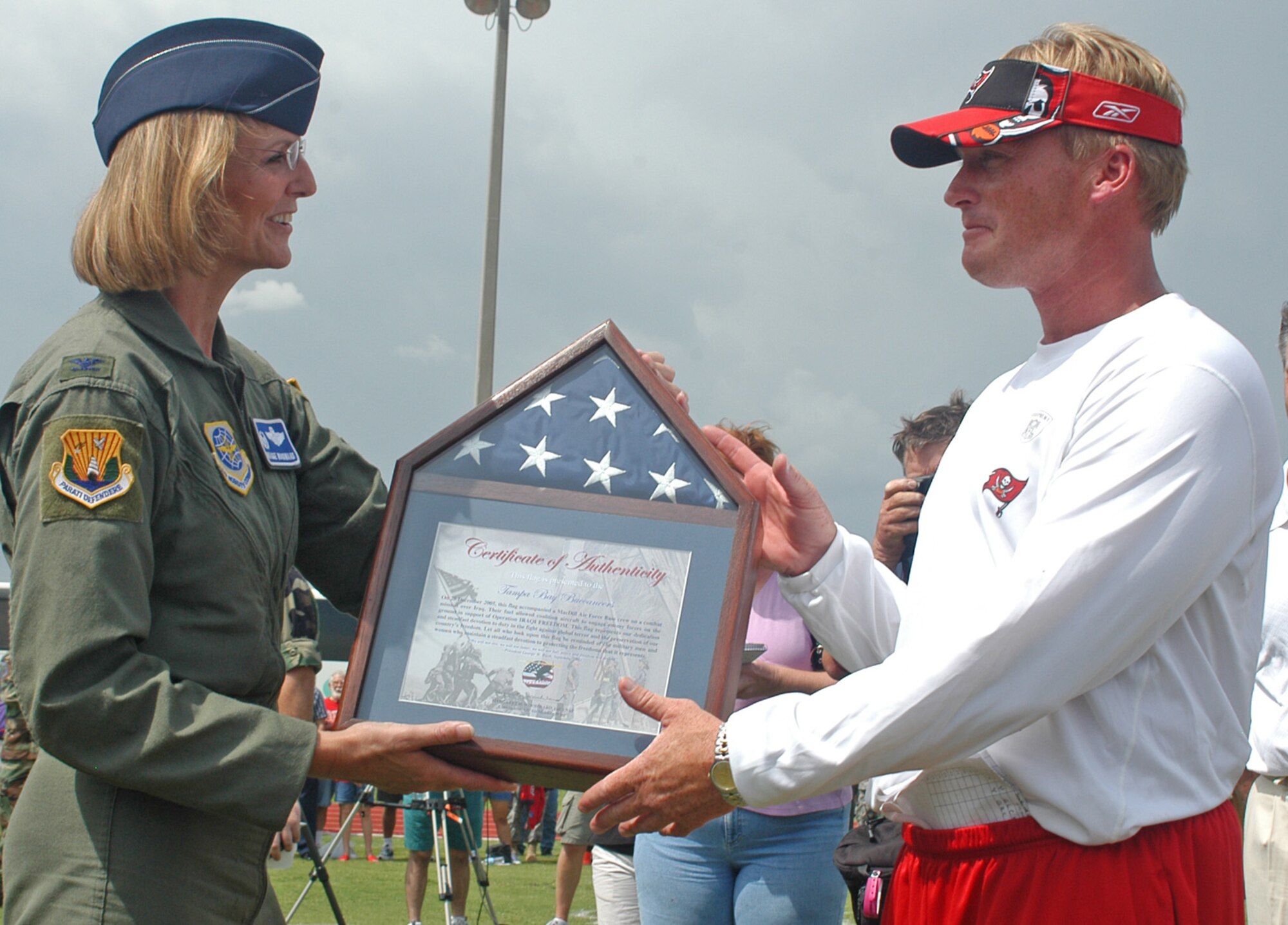 Col. Maggie Woodward, 6th Air Mobility Wing commander, presents a framed flag to Jon Gruden, Tampa Bay Buccaneers head coach, after the pre-game, walkthrough practice held at MacDill AFB, Fla., Friday, Aug. 8.  The flag was flown over Iraq by a flight crew deployed from MacDill.