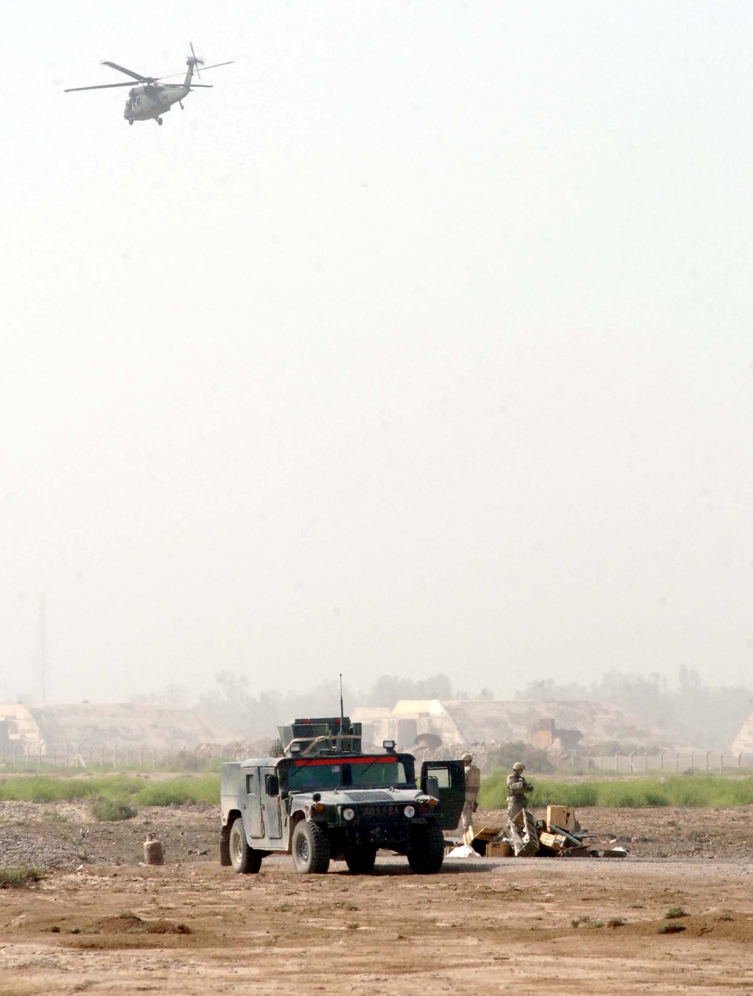 As an Army UH-60 Black Hawk lands at Baghdad International Airport, Iraq, two explosive ordnance disposal technicians "safe" the range after completing two detonations to destroy ordnance. The Airmen are from the 447th Air Expeditionary Group and are part of an Air Force EOD flight responsible for a 500-square mile area around Baghdad. (U.S. Air Force photo/Staff Sgt. Bryan Bouchard)