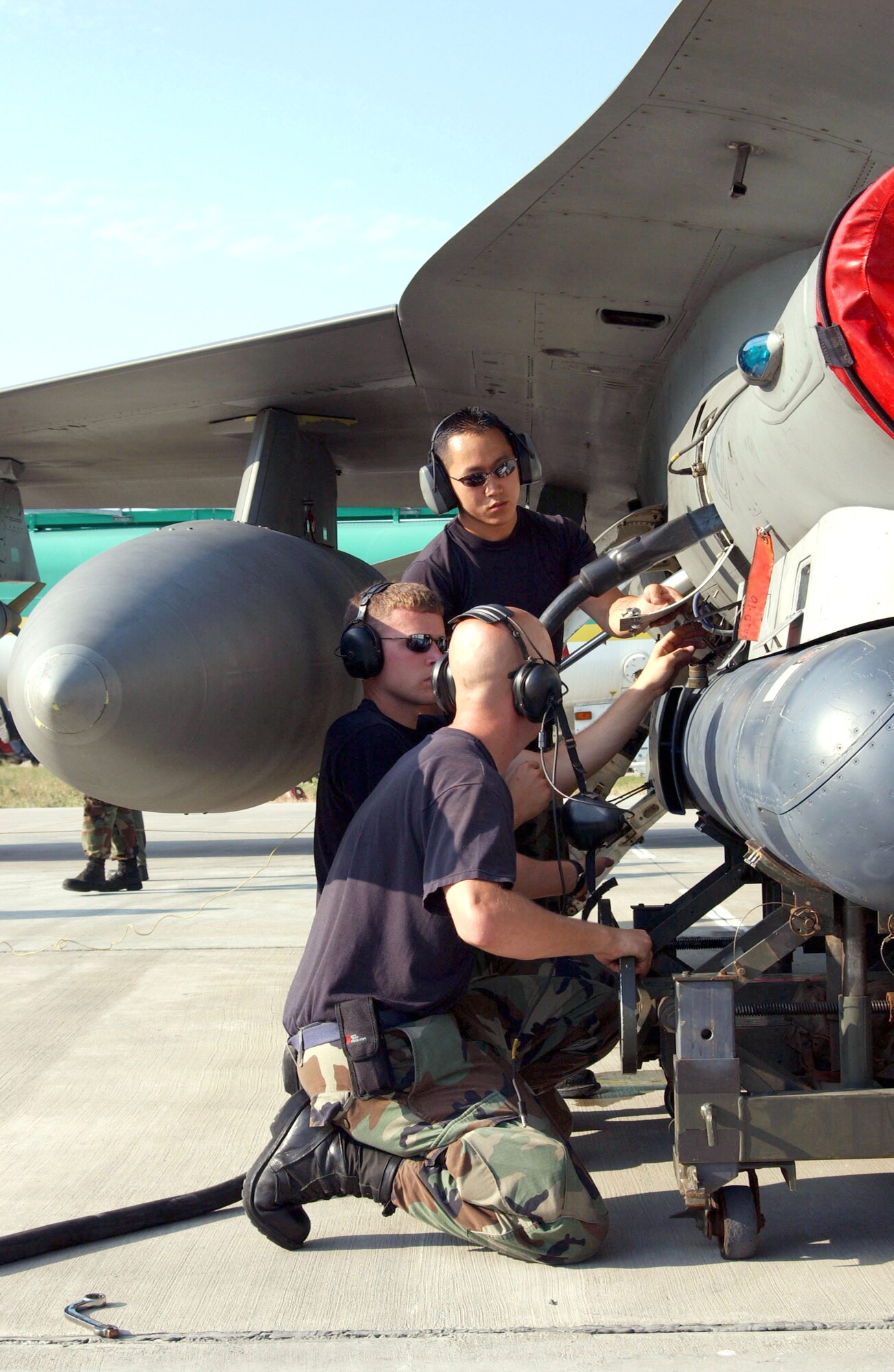 (Front to back) Staff Sgts. Jeremy Crombie and Brandon Holloway and Senior Airman Joshua Hood work together to upload a targeting pod on an F-16 Fighting Falcon on Aug. 18 during Exercise Viper Lance 2006 at Mihail Kogalniceanu Air Base, Romania. The Airmen are maintainers assigned to the 22nd Expeditionary Fighter Squadron. (U.S. Air Force photo/Senior Airman Eydie Sakura)