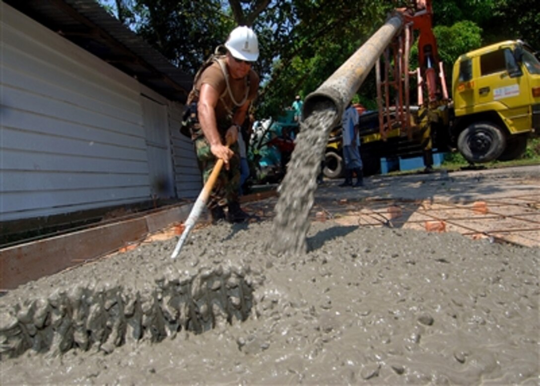 U.S. Navy Ensign Brian Christner levels out freshly poured concrete for a driveway at a local school in Tarakan, Indonesia as part of a community relations project with the Military Sealift Command hospital ship USNS Mercy, Aug. 15, 2006.  