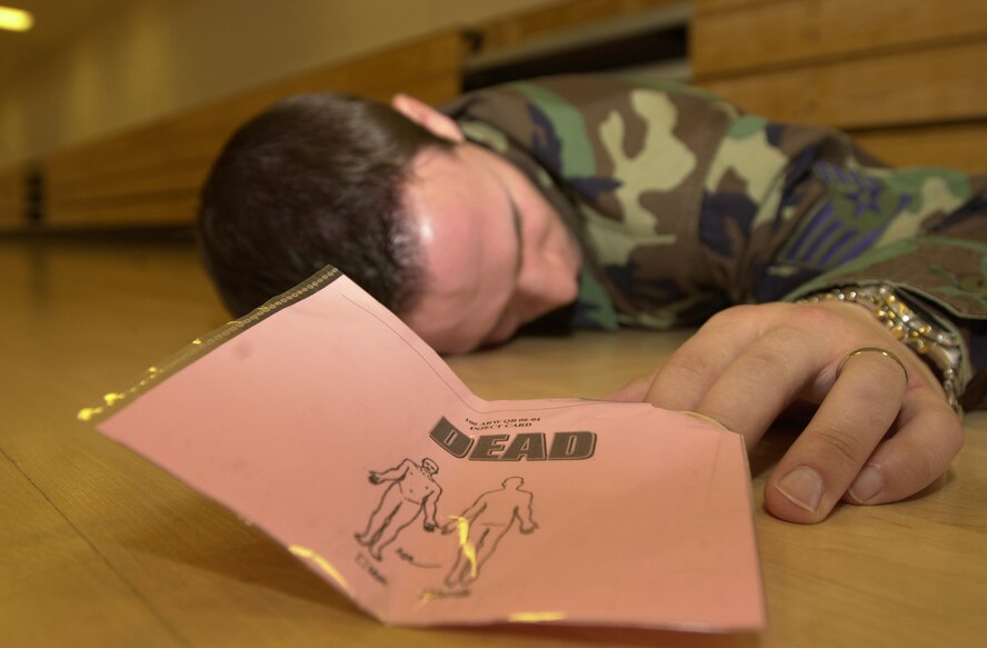 An Airman simulates being killed by sarin gas during a weapon of mass destruction exercise Aug. 15 at RAF Mildenhall. The base-wide exercise tested the base's ability to respond to a WMD attack in cooperation with local British emergency services. (U.S. Air Force photo by Senior Airman Clark Staehle)