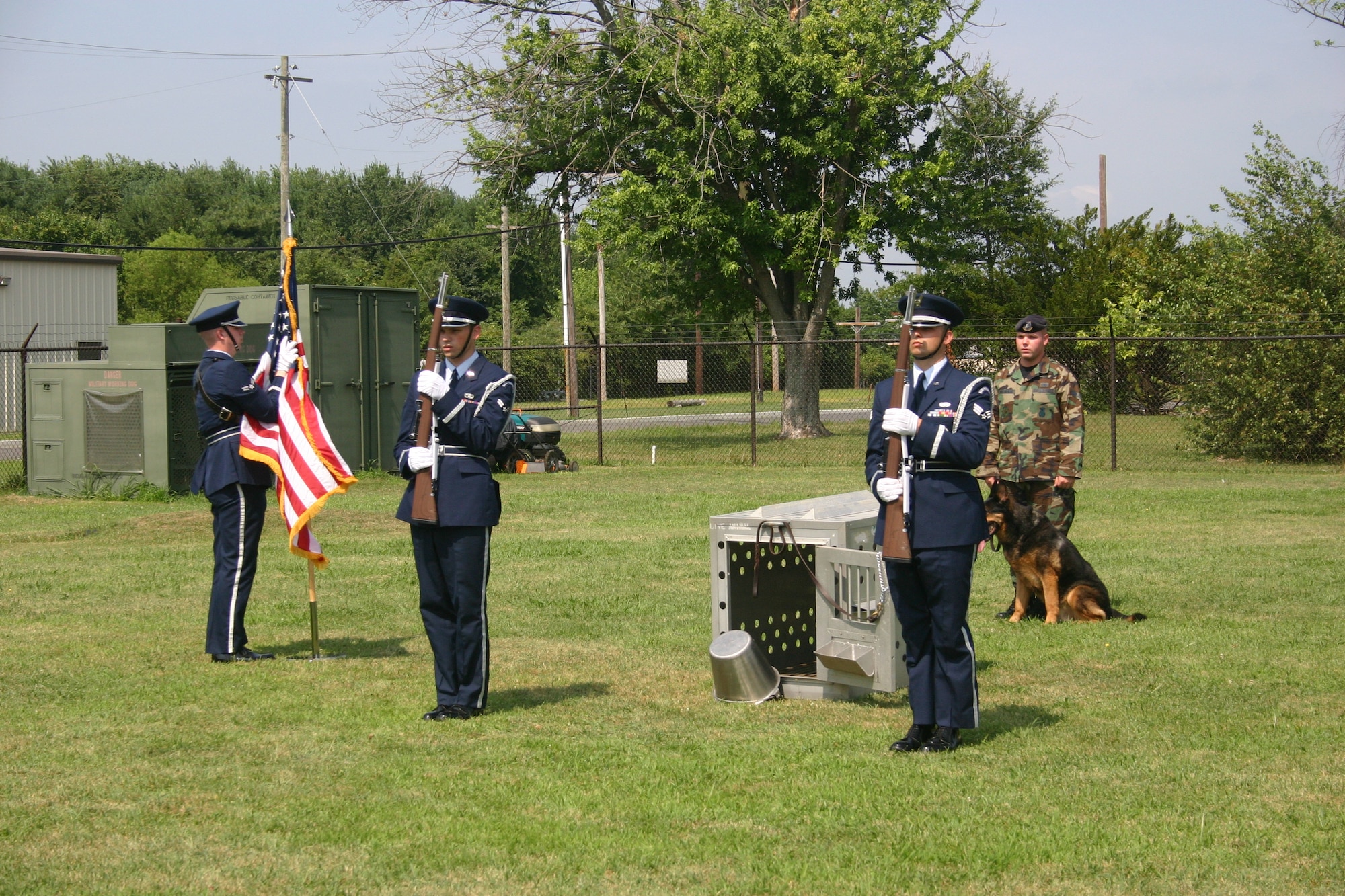 McGuire Honor Guard members stand before “The Empty Dog” display that signifies the bond between a handler and his dog. Behind them stands Airman Vollweiler and his dog, Black, during the K-9’s retirement ceremony. Black and two of his fellow K-9s were adopted by their former handlers and went home with them after the ceremony.