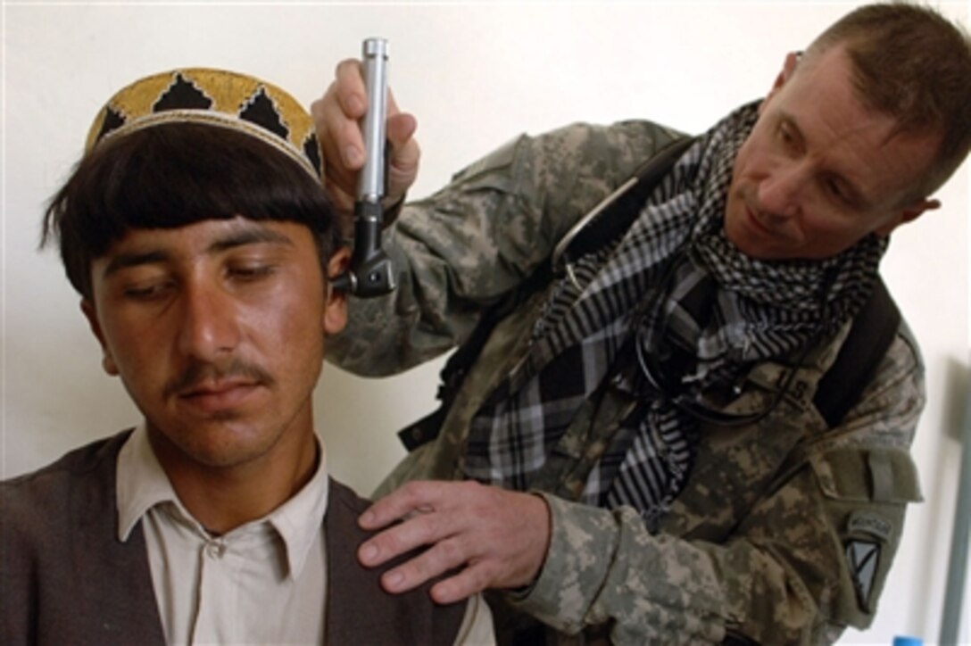 A soldier from the U.S. Army's 710th Combat Support Hospital looks into the ear of a patient during a medical civil action project being conducted at a school in the Khowst province of Afghanistan on July 22, 2006.  