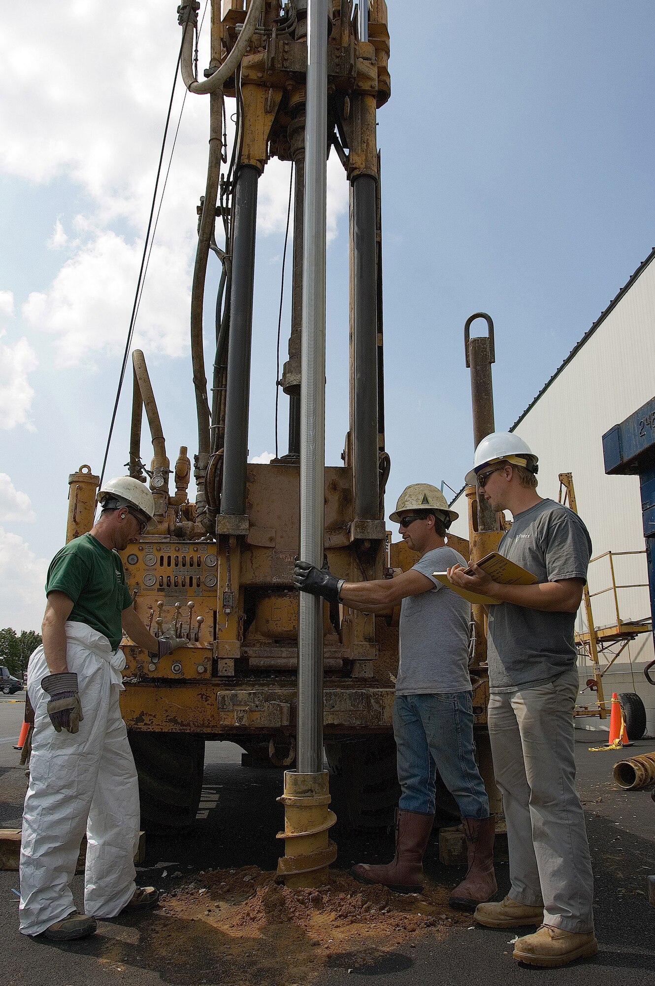 Scott Pitz (right), a field geologist from URS Corporation is overseeing Aaron Eichelberger (left), lead driller, and Jeffery Rausa (middle), a driller helper, both from SGS Environmental Services, Inc. as they install a 20-foot stainless steel well screen.  SGS Environmental Services, Inc. is a subcontractor for URS Corp. The cleanup effort is removing chlorinated solvents, which were disposed of in the ground when the base first began operations, according to Charles Mikula, 436th Civil Engineer Squadron environmental flight chief. This is not a concern for public health since no one drinks the water, he said. (U.S. Air Force photo/Roland Balik)
