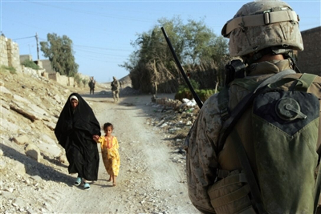 Lance Cpl. James E. Connelly, a 19-year-old rifleman from Cedar Grove, N.J., passes by an Iraqi woman and her daughter during a patrol in Sadiquiyah, Iraq, Aug. 18, 2006. Connelly and other Marines assigned to I Company, 3rd Battalion, 2nd Marine Regiment conducted the patrol to show their prescence within the community. 