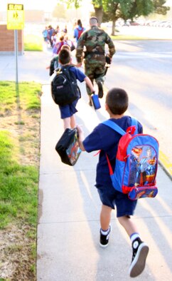 Gunfighter children race toward the Base Primary School yesterday, eager to start the new school year. 