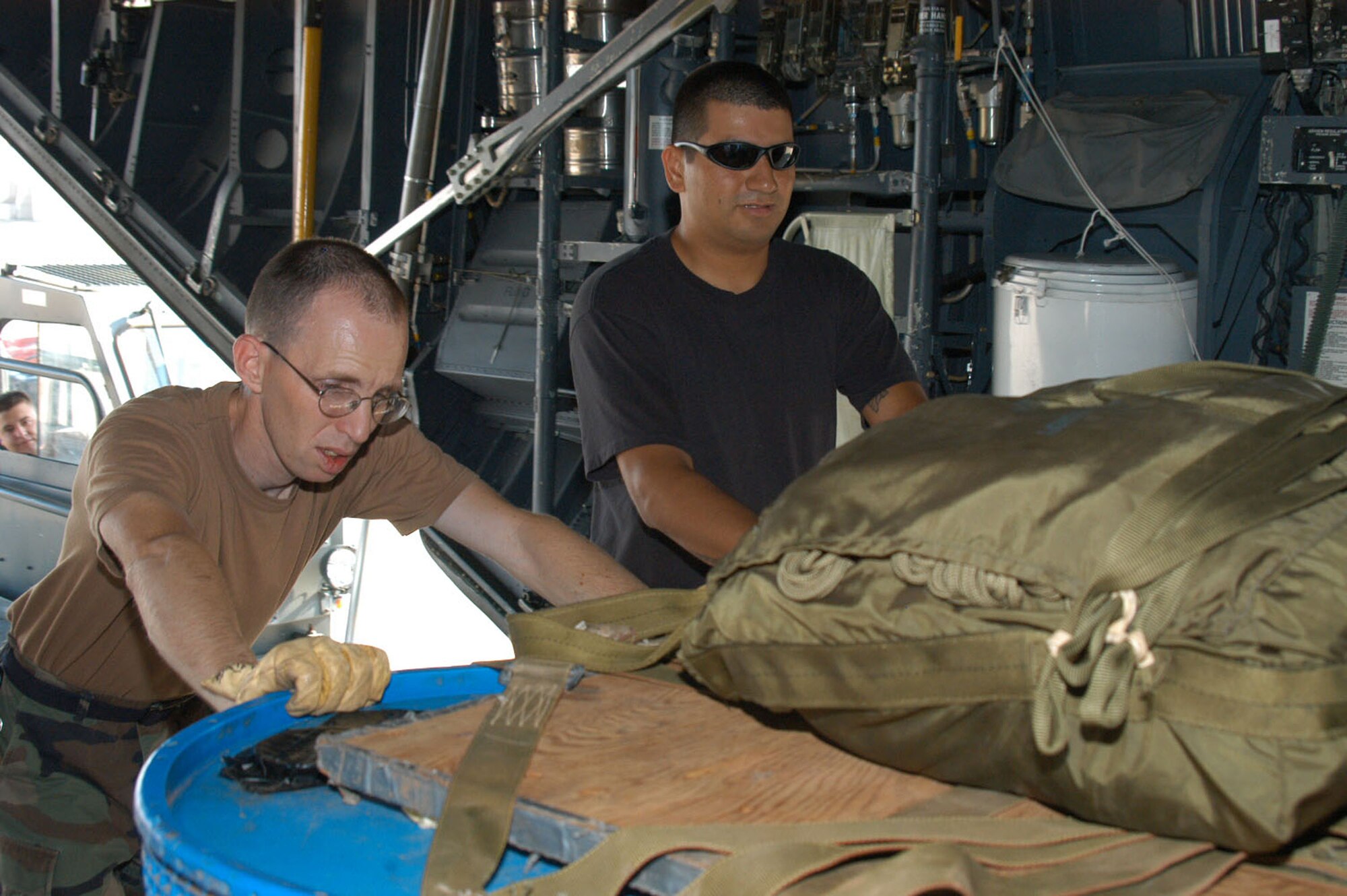 Left, Staff Sgts. Sean Herzog and Joel Salazar, 317th OSS, push in a pallet of cargo onto a C-130. The tanks contain water to simulate the weight that would be dropped.                                