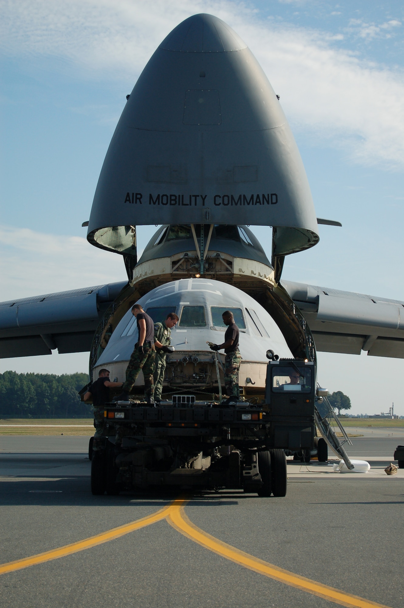 (Left to right) Staff Sgt. John Rollins, 436th Aerial Port Squadron, Airman 1st Class Shain Brower, 436th APS, Staff Sgt. Stuard Smith II, 9th Airlift Squadron, and Senior Airman Joseph Moseley, 436th APS, load the flight deck from the C-5 mishap onto another Dover C-5 for transport to Robins Air Force Base, Ga. The flight deck will be used to as a training simulator to help prevent future C-5 mishaps. (U.S. Air Force photo/Airman 1st Class James Bolinger)