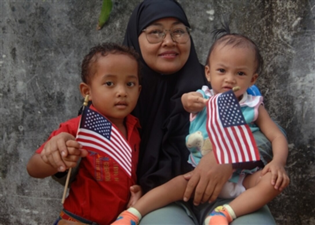 A  local family displays their United States flags during a medical and dental civic action project held by the Military Sealift Command hospital ship USNS Mercy, in Tarakan, Indonesia, Aug. 14, 2006. The  Mercy is off the coast to provide humanitarian and civic assistance to the people of this coastal city. 