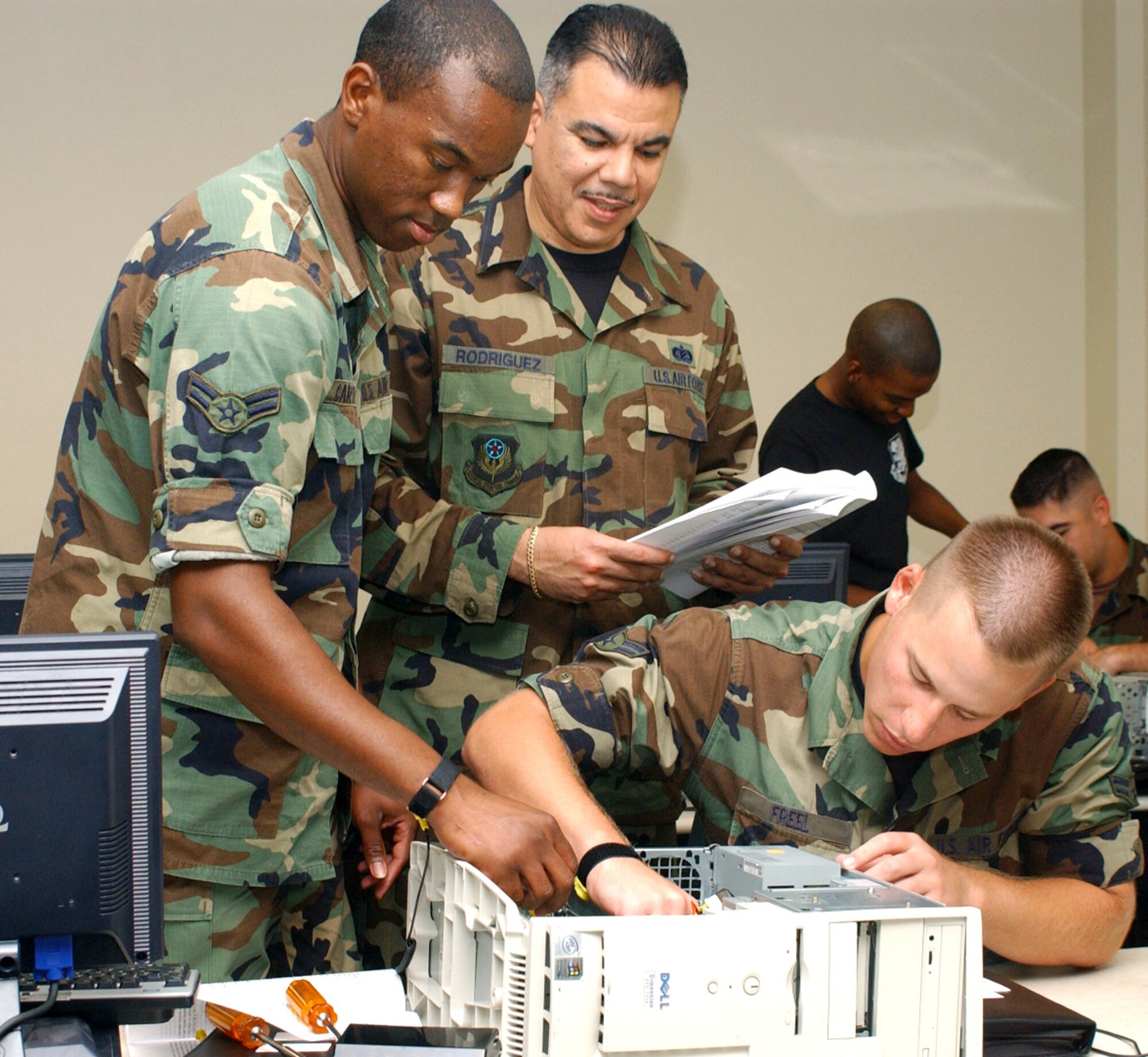(From left) Airman 1st Class David Carter, Tech. Sgt. Gilbert Rodriguez and Airman 1st Class David Freel install a hard drive during an information management course recently at Keesler Air Force Base, Miss. Airmen Carter and Freel are Sergeant Rodriguez' students. Sergeant Rodriguez, from Hurlburt Field, Fla., is at Keesler on a six-month temporary duty assignment augmenting the 336th Training Squadron training team.  (U.S. Air Force photo/Kemberly Groue)