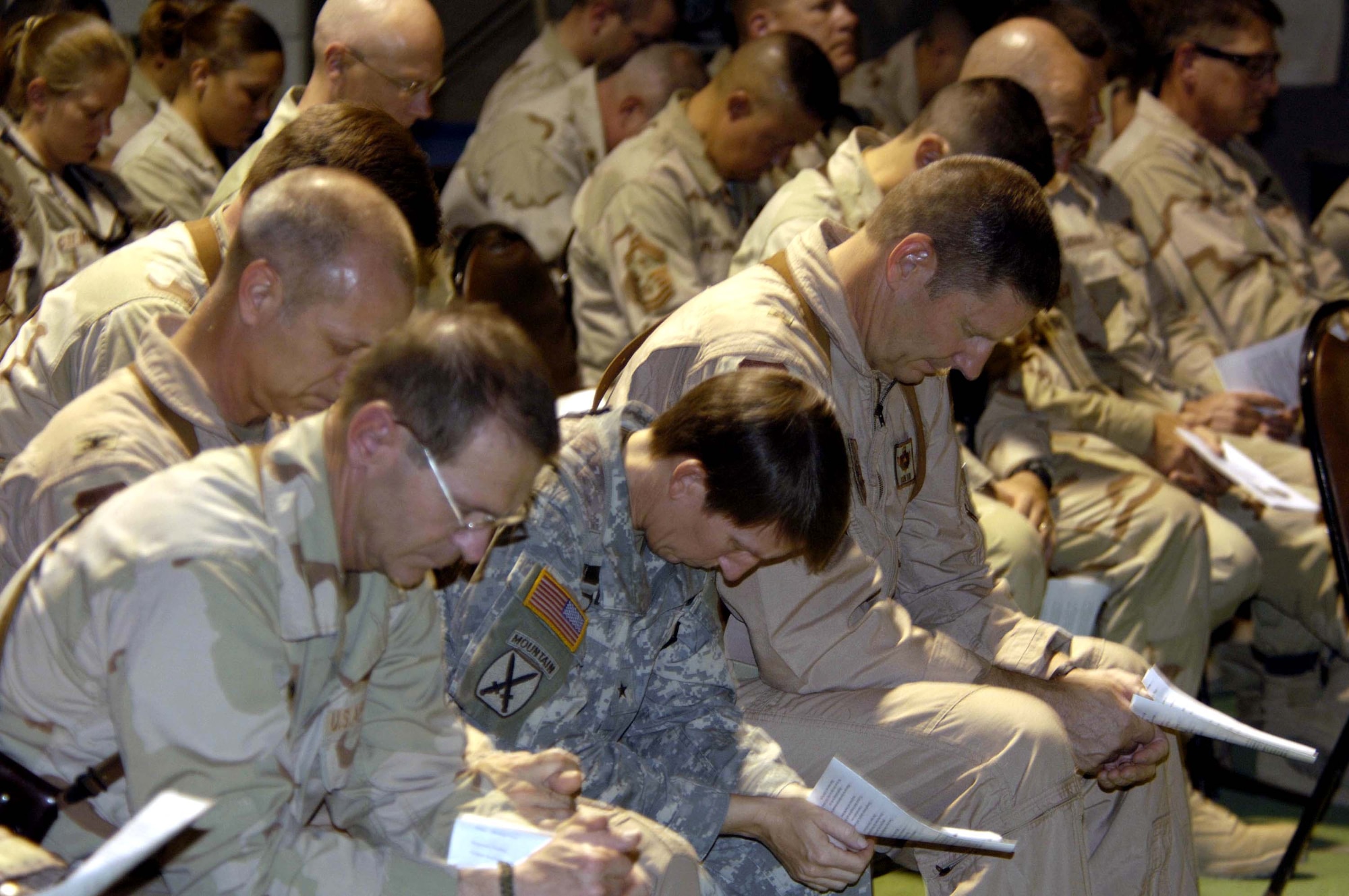 Airmen and Soldiers at Balad Air Base, Iraq, share a moment of prayer during a memorial service for Master Sgt. Brad A. Clemmons Aug. 24. The ceremony, attended by about 400 Airmen from the 332nd Air Expeditionary Wing and Soldiers of the 3rd Corps Support Command, honored Sergeant Clemmons who died Aug. 21 when his vehicle struck an improvised explosive device near Taji, Iraq. (U.S. Air Force photo/Senior Airman Andrew Oquendo)