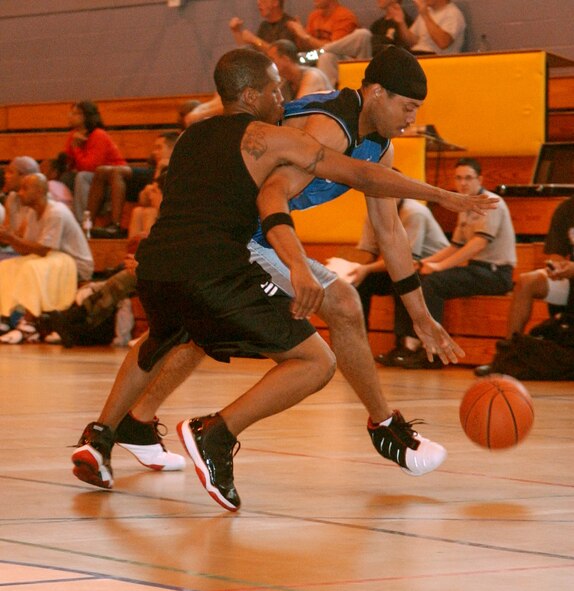 Corey Fletcher, 100th Maintenance Squadron, charges past Jermaine James, 100th Security Forces Squadron, to score at the three-on-three basketball tournament during the 2006 Wing Sports Day at RAF Mildenhall, England, Aug. 18. The 100th MXS A-Team won the game 21-10. (U.S. Air Force photo by Staff Sgt. Tyrona Pearsall)