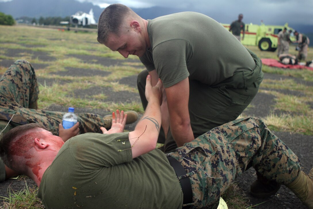 Lance Cpl. Christopher M. Garrett, combat lifesaver, Marine Heavy Helicopter Squadron 363, aplies pressure to a Marine with an open wound to stop the flow of blood, Aug. 25, during a mass casualty drill at West Field here.