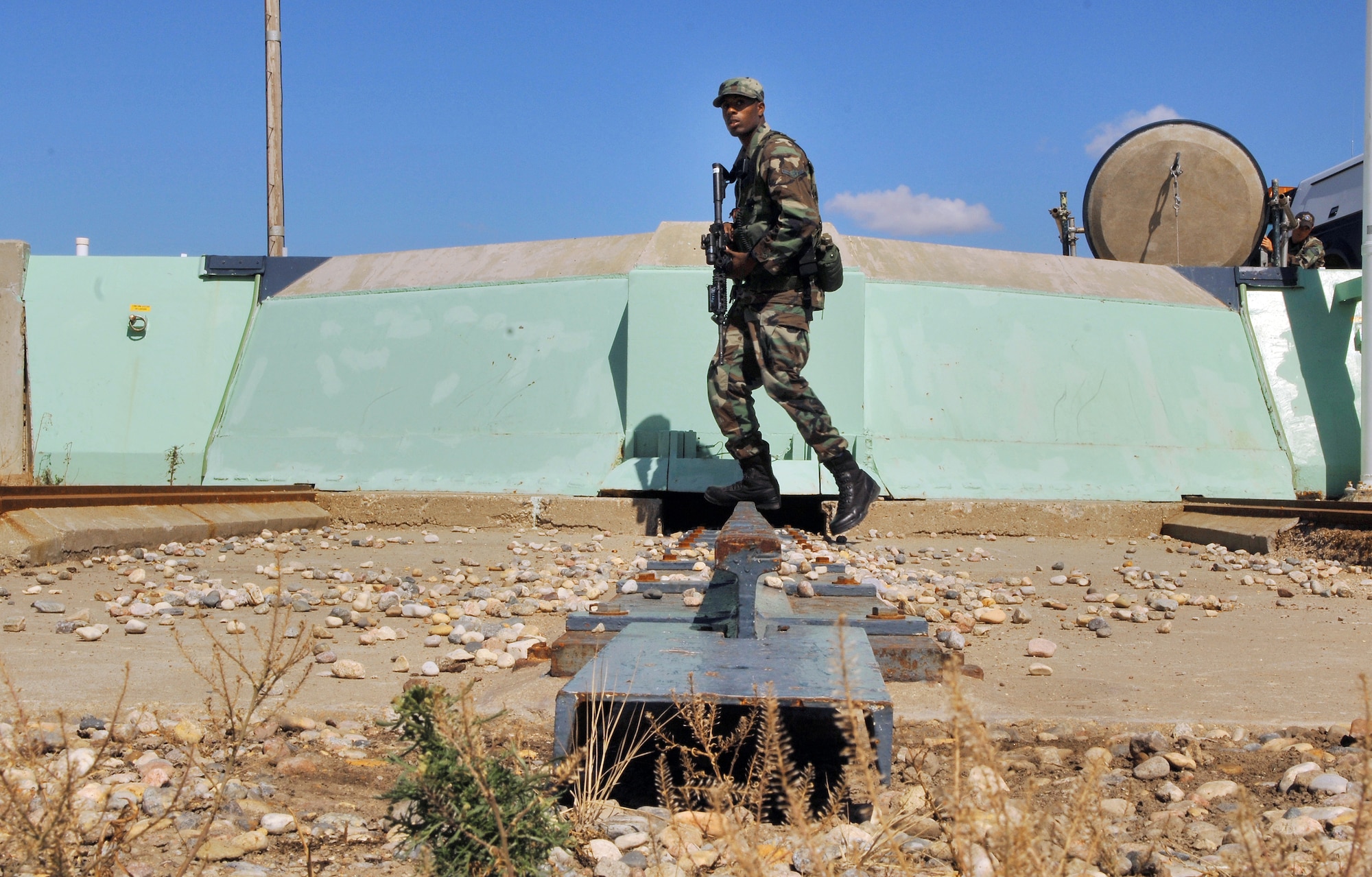 Airman Jeremey Yancey patrols a Minuteman III intercontinental ballistic missile launch facility during the annual code change Aug. 25. The Airman is a security escort team member with the 791st Missile Security Forces Squadron at Minot Air Force Base, N.D. The green painted wall is the side of the 110-ton launcher closure door that protects the missile. (U.S. Air Force photo/Airman 1st Class Chris Boitz)
