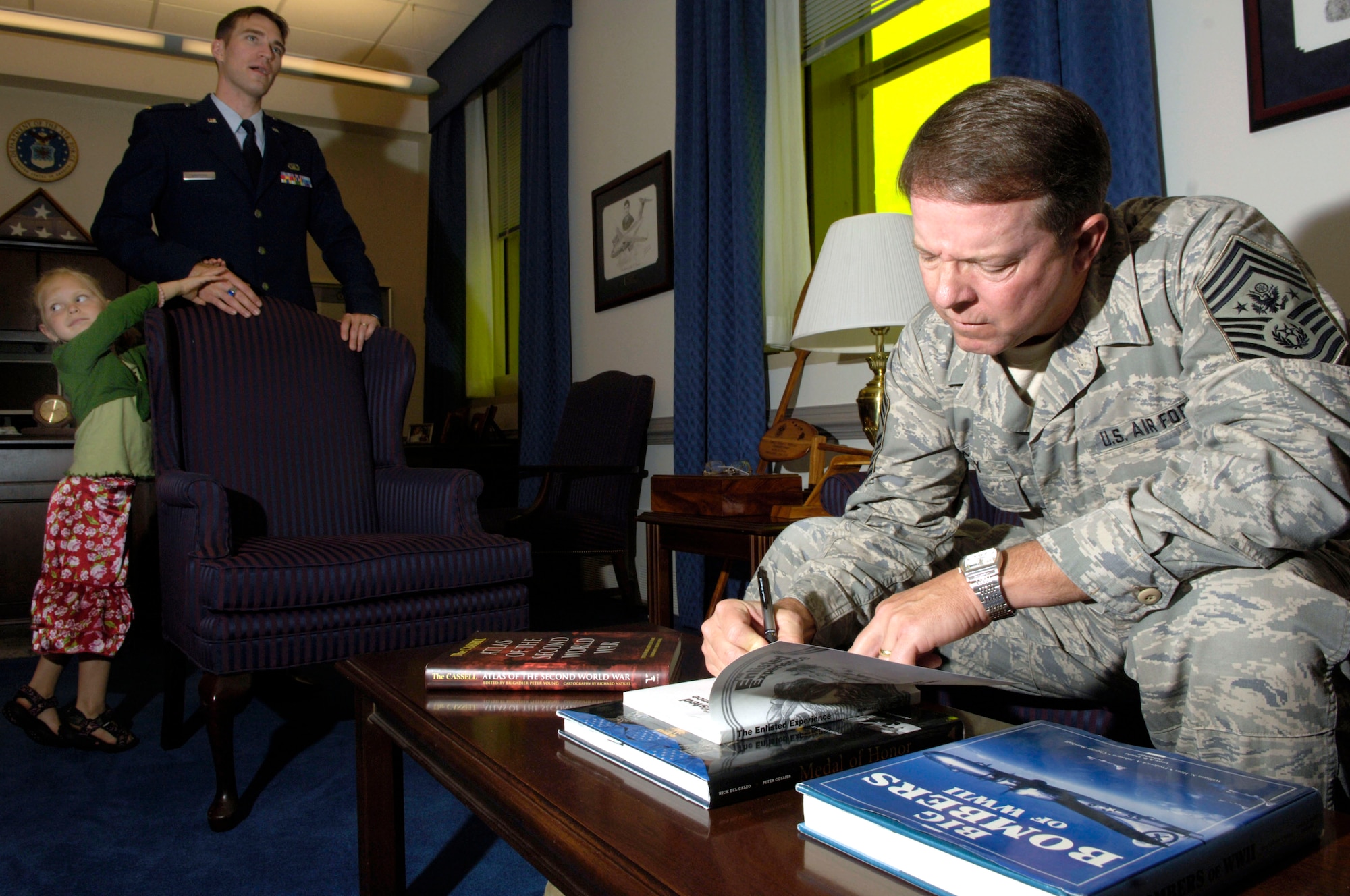 Second Lt. Paul Griffith and his daughter, Emily, stand by as Chief Master Sgt. of the Air Force Rodney J. McKinley signs the book, "The Enlisted Experience," for him. Chief McKinley met Lieutenant Griffith, his wife, Catherine, and their two children on a hop from Peterson Air Force Base, Colo., to Washington, D.C. (U.S. Air Force photo/Tech. Sgt. Cohen A. Young)
