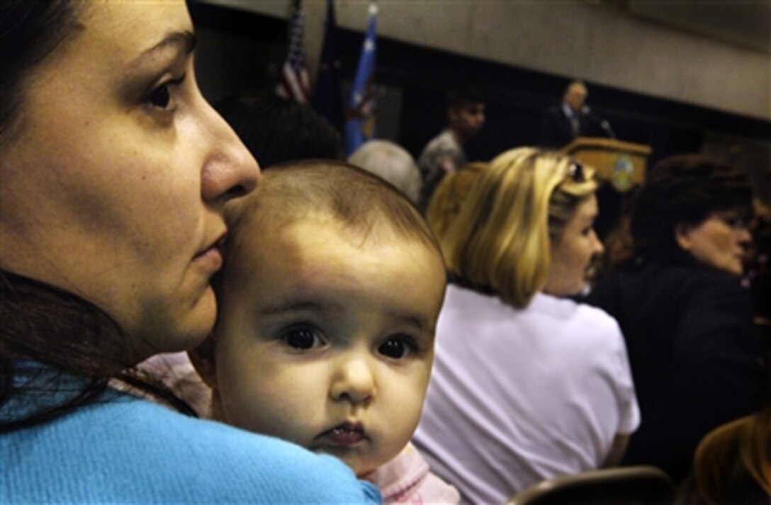 Joli Abshira, wife of U.S. Army Spc. Morgan Abshira, holds her daughter as she listens to Defense Secretary Donald H. Rumsfeld speak to approximately 600 family members of the 172nd Stryker Brigade Combat Team in a gymnasium at Fort Wainwright, Alaska, Aug 26, 2006. The uniformed members of the 172nd are currently deployed in support of Operation Iraqi Freedom.