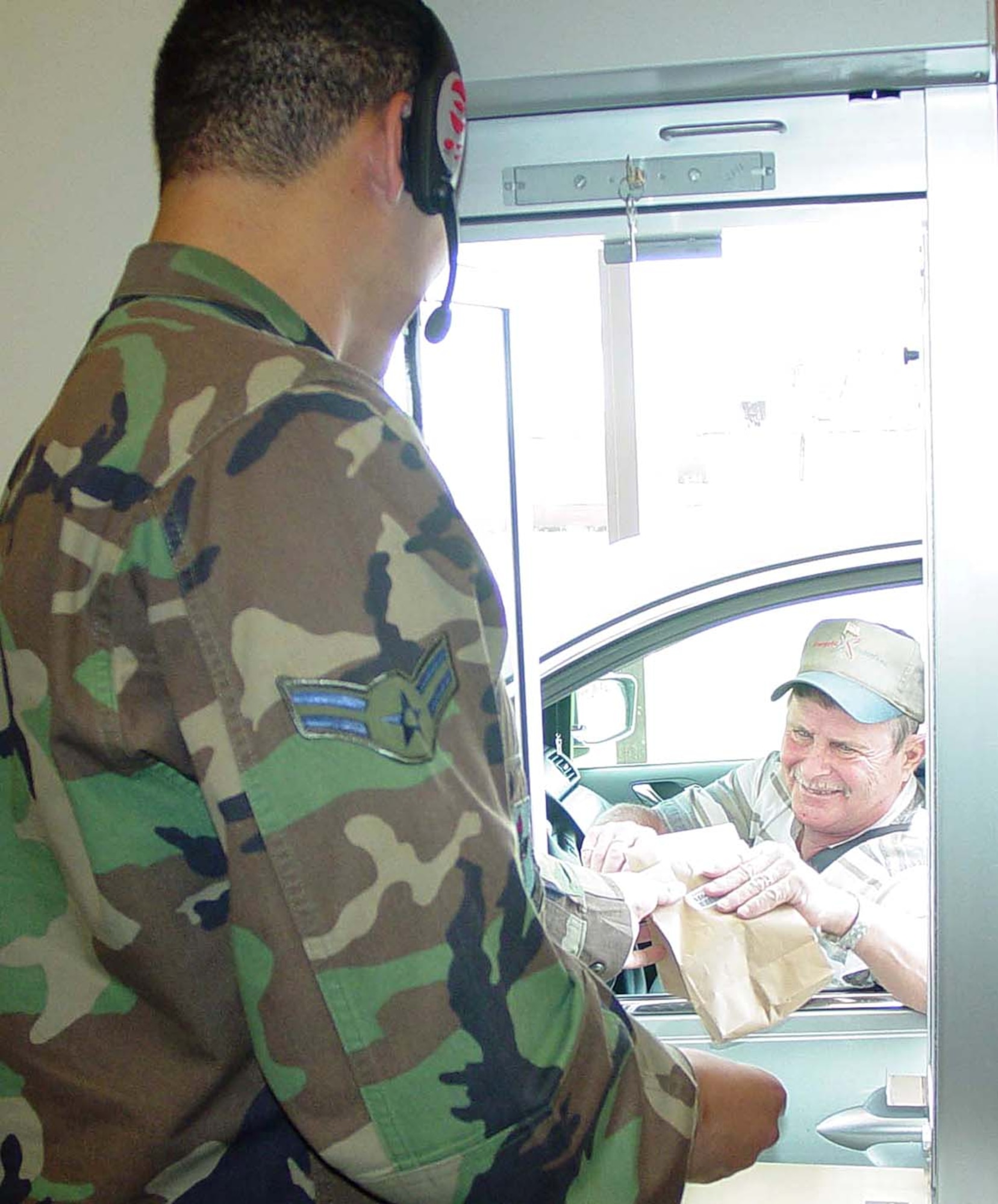 Airman 1st Class Eduardo hands a prescription to retiree Charley McNaron at the temporary satellite pharmacy drive-through window. Airman Caetano is a pharmacy technician with the 81st Medical Support Squadron pharmacy flight at Keesler Air Force Base, Miss. (U.S. Air Force photo)