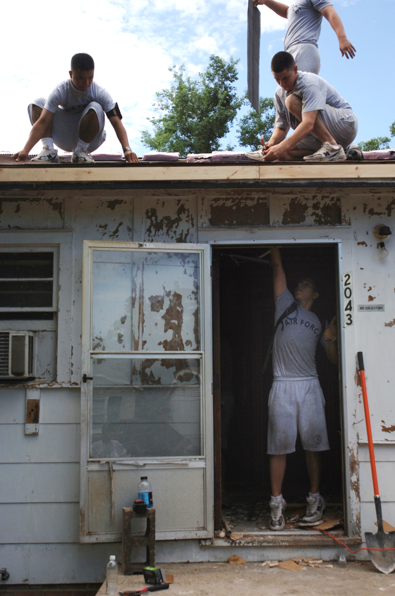 Trainees from Keesler Air Force Base, Miss., help repair a water-damaged roof in a house in Biloxi, Miss., Aug. 25. The civilian's house was heavily damaged by Hurricane Katrina one year ago. The Airmen are with the 332nd Training Squadron at Keesler AFB. (U.S. Air Force photo/Tech. Sgt. Cecilio Ricardo Jr.)