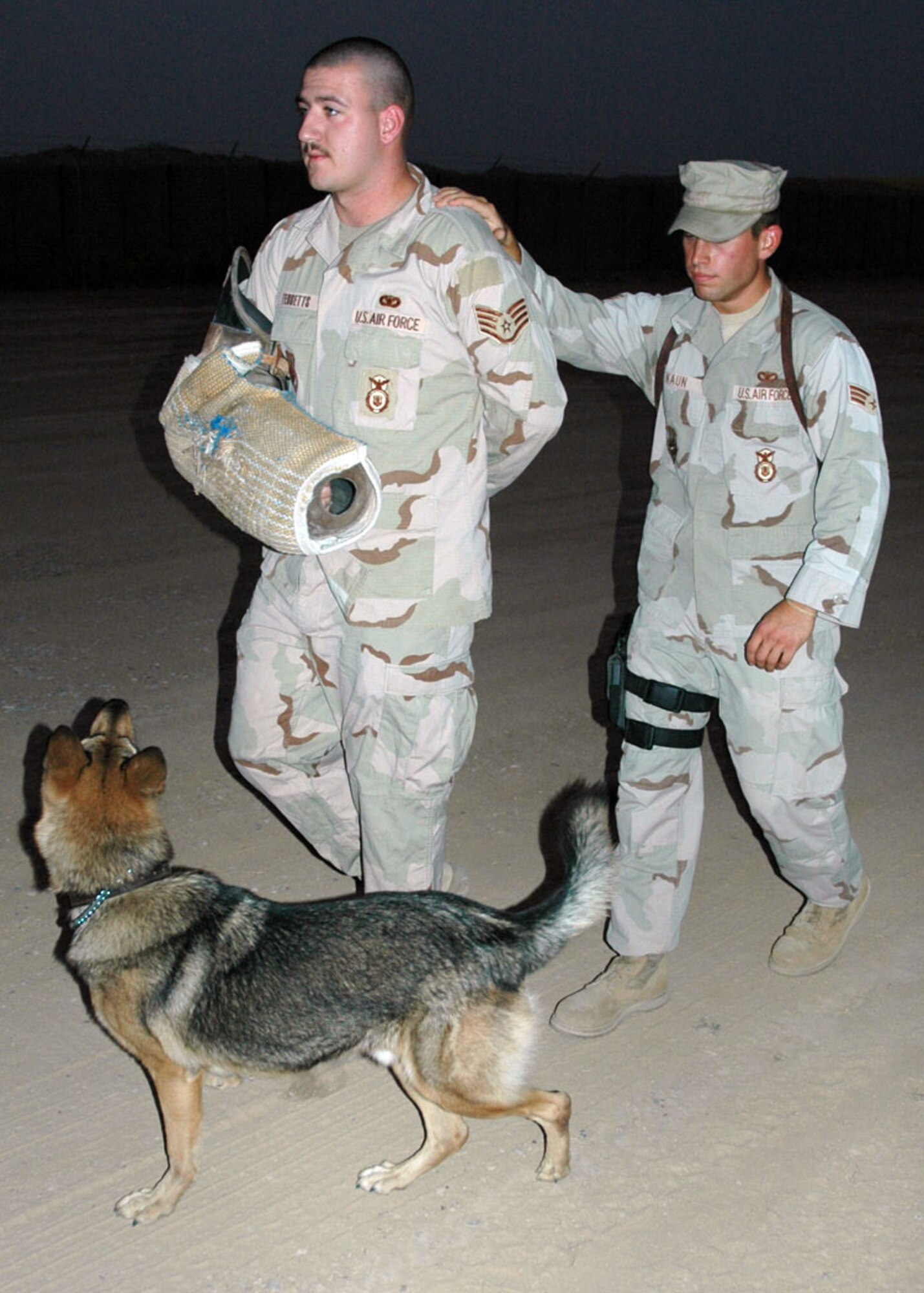 Senior Airman Steven Kaun, 506th Expeditionary Security Forces Squadron Military Working Dog Section, trains with Argo, his canine partner, on escort drills with the help of Staff Sgt. Clayton Tebbetts, a fellow MWD handler. (Photo by Staff Sgt. Stacy Fowler)