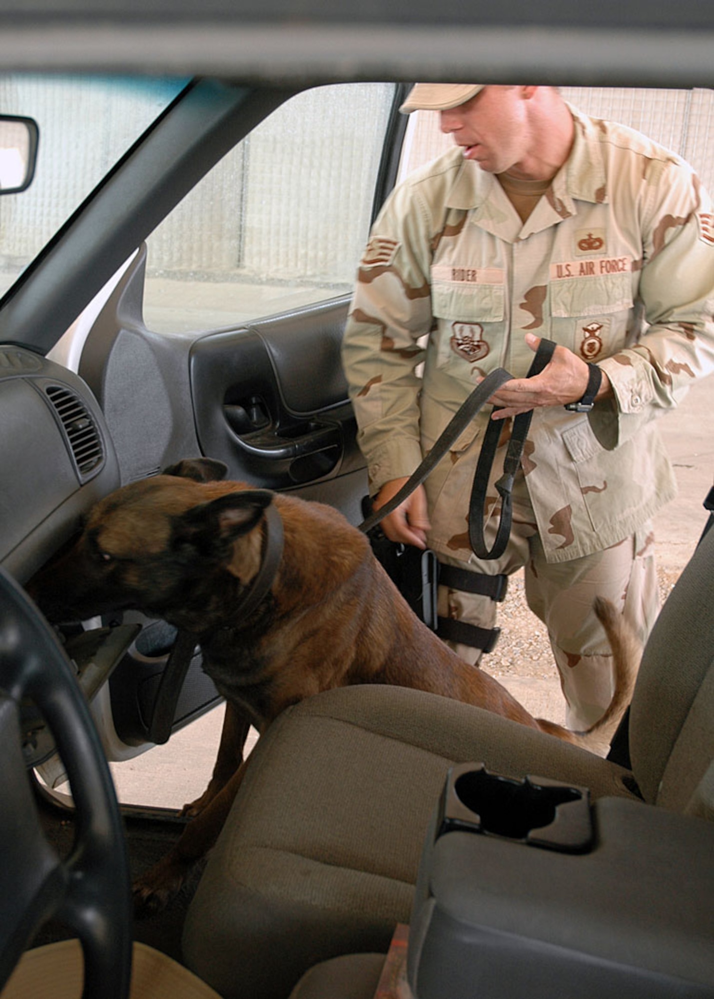 Staff Sgt. William Rider and his partner Rex, 506th Expeditionary Security Forces Squadron Military Working Dog Section, inspect vehicles at the search pit.  All vehicles coming from off base are inspected to ensure no explosives or weapons are able to get on base. (Photo by Staff Sgt. Stacy Fowler)