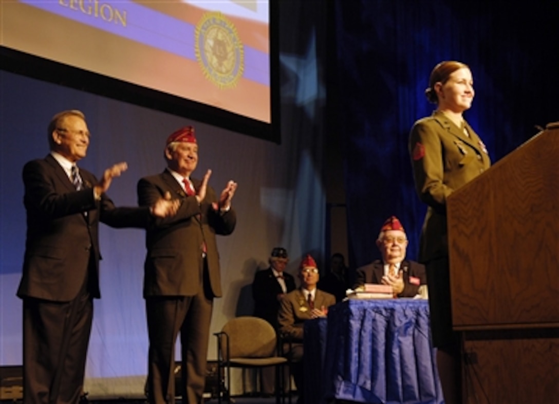 Secretary of Defense Donald H. Rumsfeld and American Legion National Commander Thomas L. Bock applaud U.S. Marine Corps Sgt. Kristianna M. Huntington during the 88th American Legion national convention in Salt Lake City, Utah, on Aug. 29, 2006.  Huntington is one of five service members presented the American Legion's Spirit of Service Award for outstanding volunteer service in their local communities.  Rumsfeld addressed the American Legion members and their guests.  