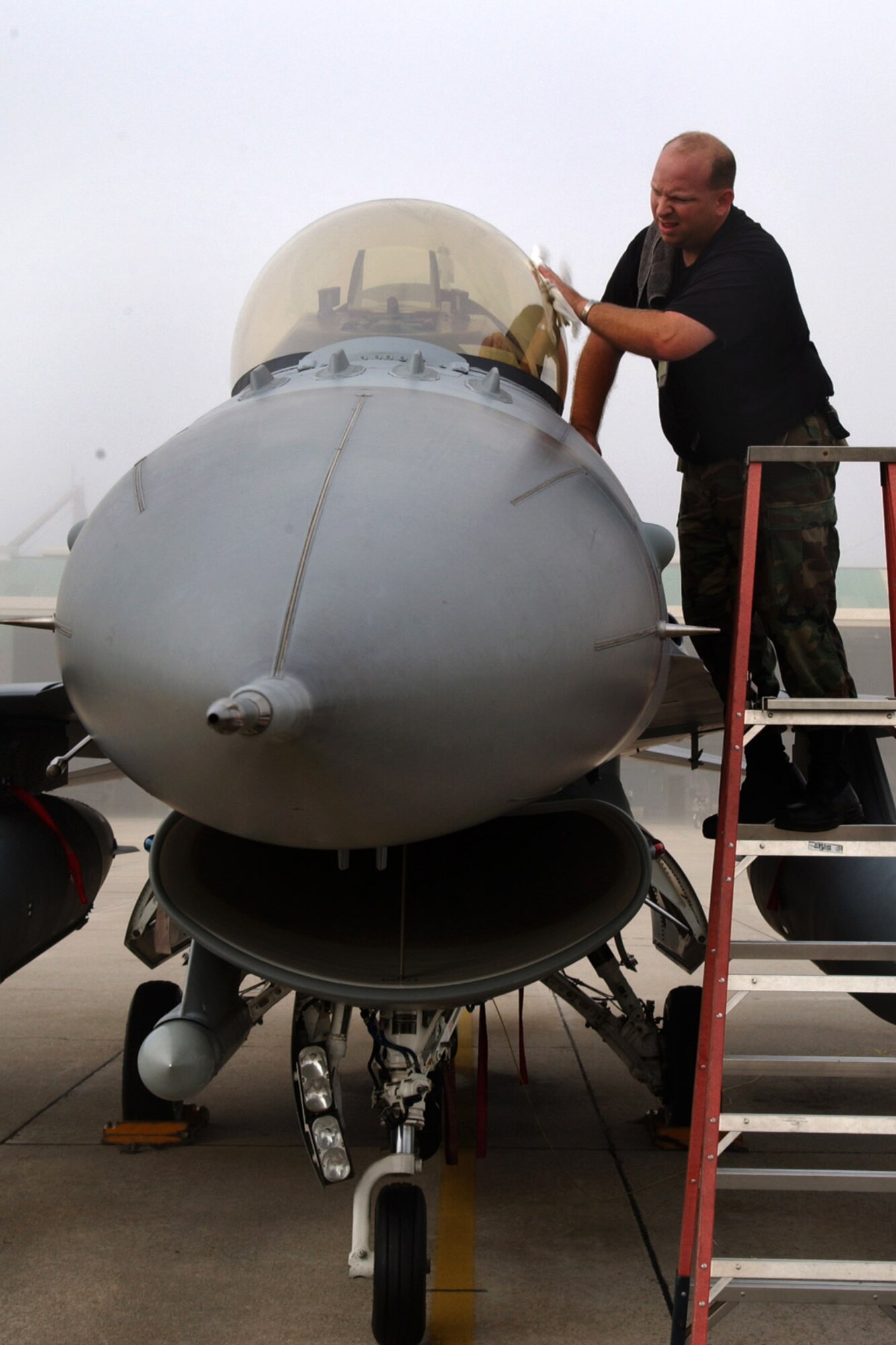 Tech. Sgt. Edgar Miller wipes moisture off the canopy of an F-16 Fighting Falcon in preparation for takeoff from McEntire Air National Guard Base, S.C., Aug. 28. Members of the 169th Fighter Wing are filling an air expeditionary force role for Pacific Air Forces. Sergeant Miller is assigned to the 169th Aircraft Maintenance Squadron. (U.S. Air Force photo/Tech. Sgt. Carol Smith)