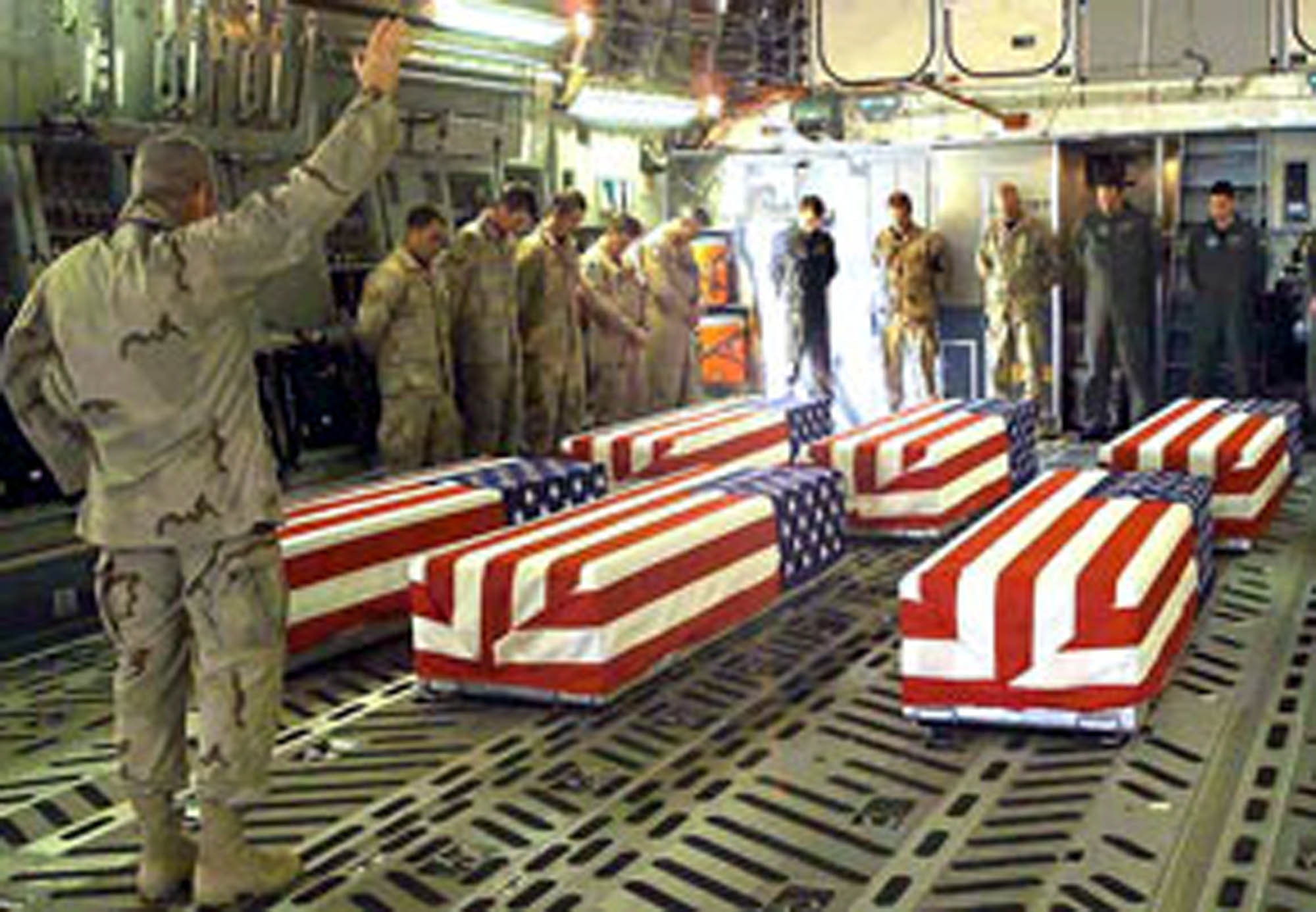 Army Chaplain (Col.) Richard Rogers leads a prayer March 25, 2003, for six Airmen killed when their HH-60G Pave Hawk helicopter crashed near Ghazni, Afghanistan, on March 23. The remains were flown to Dover Air Force Base, Del. (Photograph by U.S. Army Pvt. Terri Rorke)