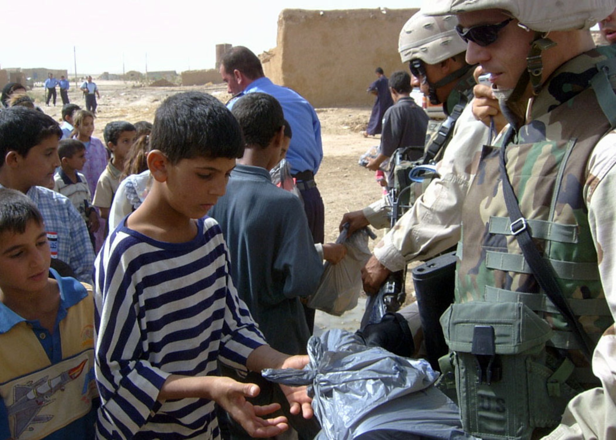 Soldiers with the Army civil affairs unit at Kirkuk Air Base, Iraq, hand out school supply packets to Iraqi school children. More than 65 volunteers from the base assembled about 9,000 packets of school supplies.  (Courtesy photo)
