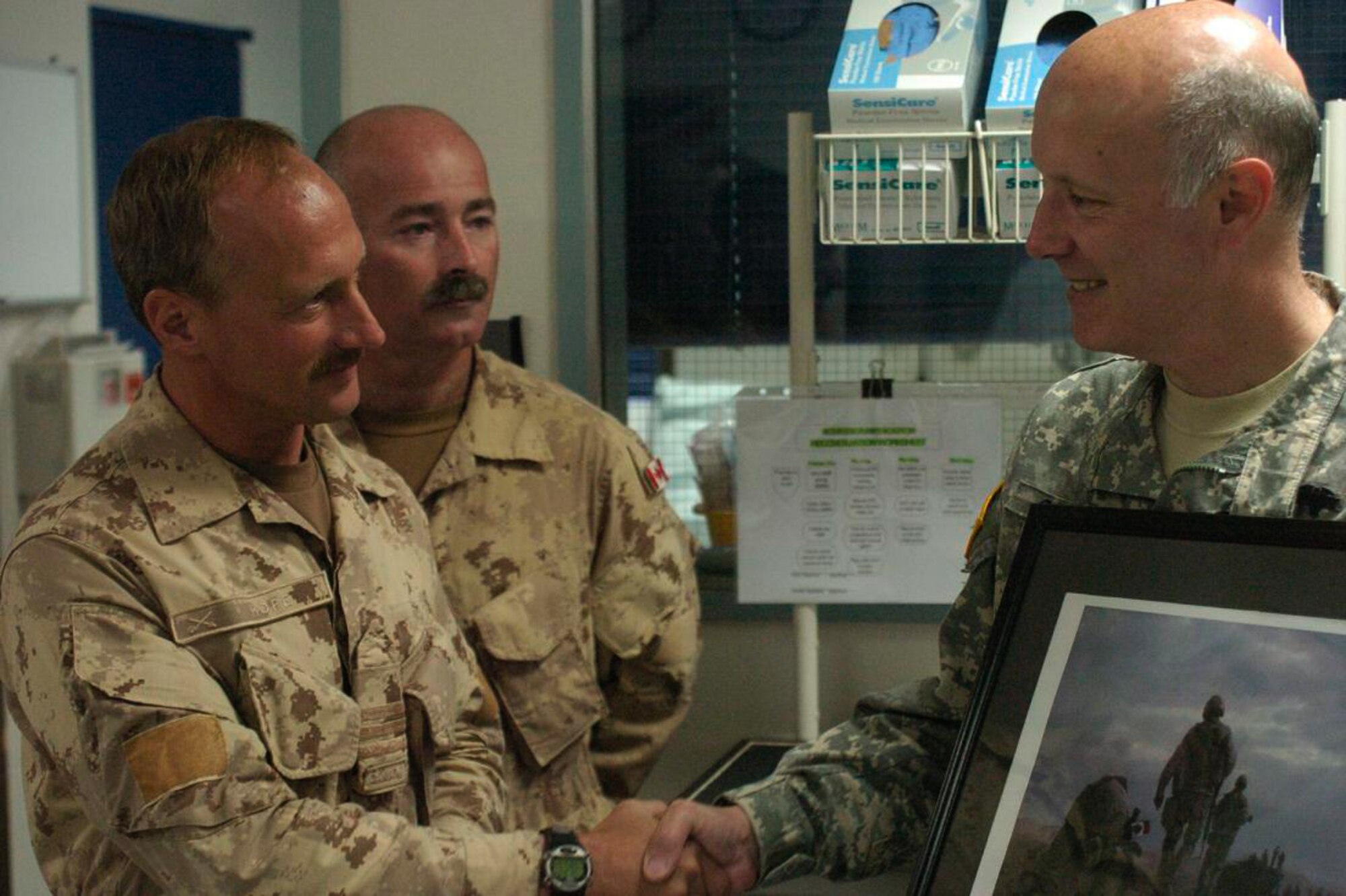 Col. Bryan Gamble accepts a print of the painting by a Canadian artist on behalf of the LRMC Intensive Care Unit. Presenting the artwork plus a large monetary donation to Fisher House were Col. Ian Hope, front, and Chief Warrant Officer Randy Northrup. Photo by Thomas Warner.