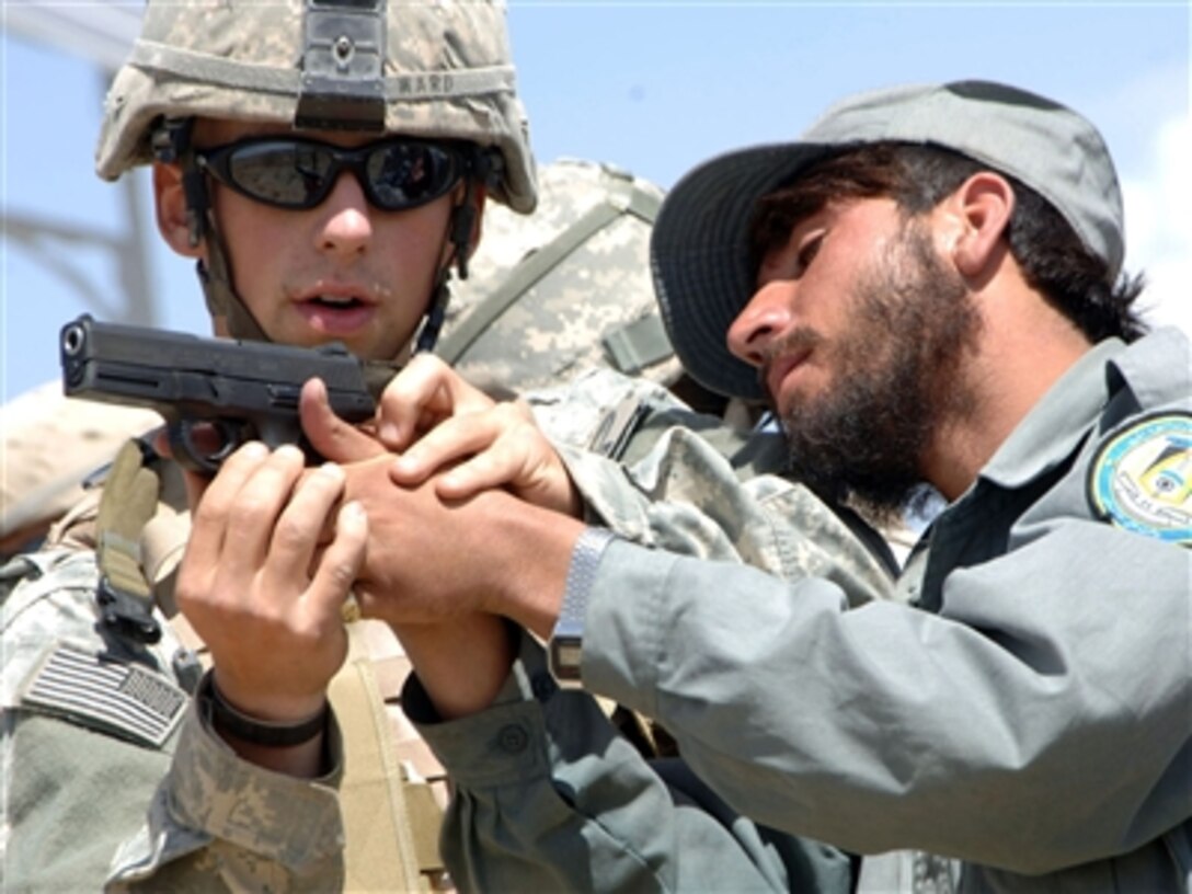 U.S. Army Spc. Patrick Ward shows an Afghanistan National Police officer the finer points of how to hold a 9 mm pistol during weapons training in Sar Hawza, Afghanistan, on Aug. 30, 2006.  Ward is attached to the Armyís 2nd Platoon, 554th Military Police Company, Stuttgart, Germany.  