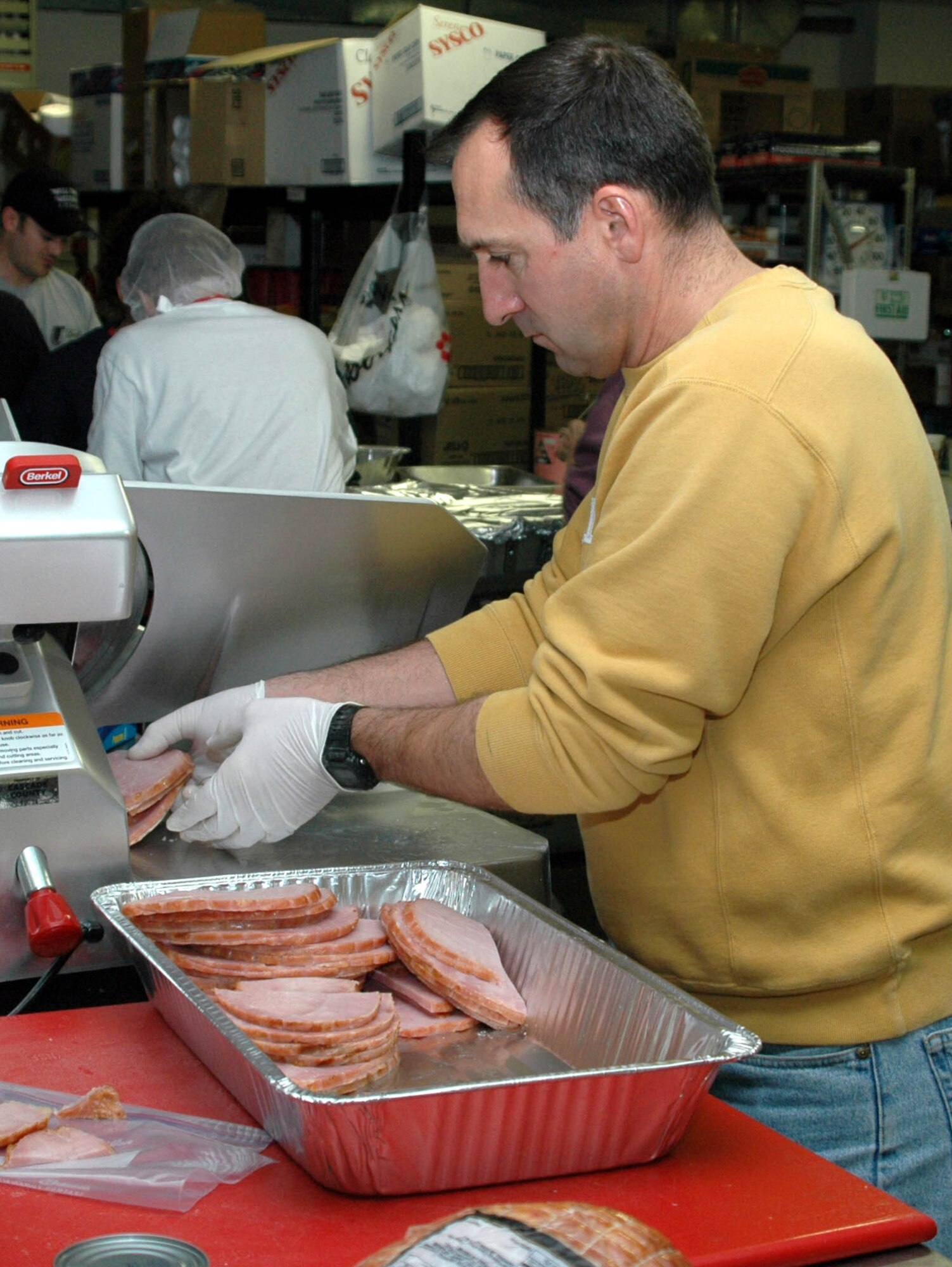 Brian Jolly, 341st MSS deputy director, slices ham for Meals-on-Wheels.