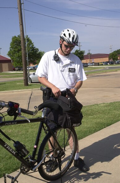 (Photo by Staff Sgt. Amanda Mills) Senior Airman Ronald Lowe, 71st Security Forces Squadron patrolman, prepares his bicycle before  beginning a patrol.