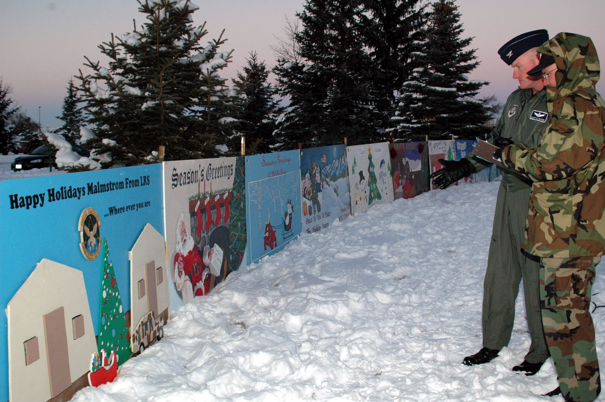 Col. Scott Gilson, 341st Operations Group commander, and Chief Master Sgt. Robert Moore, 341st Space Wing command chief, discuss scoring for the annual Holiday Card contest during festivities at the Grizzly Bend Club.