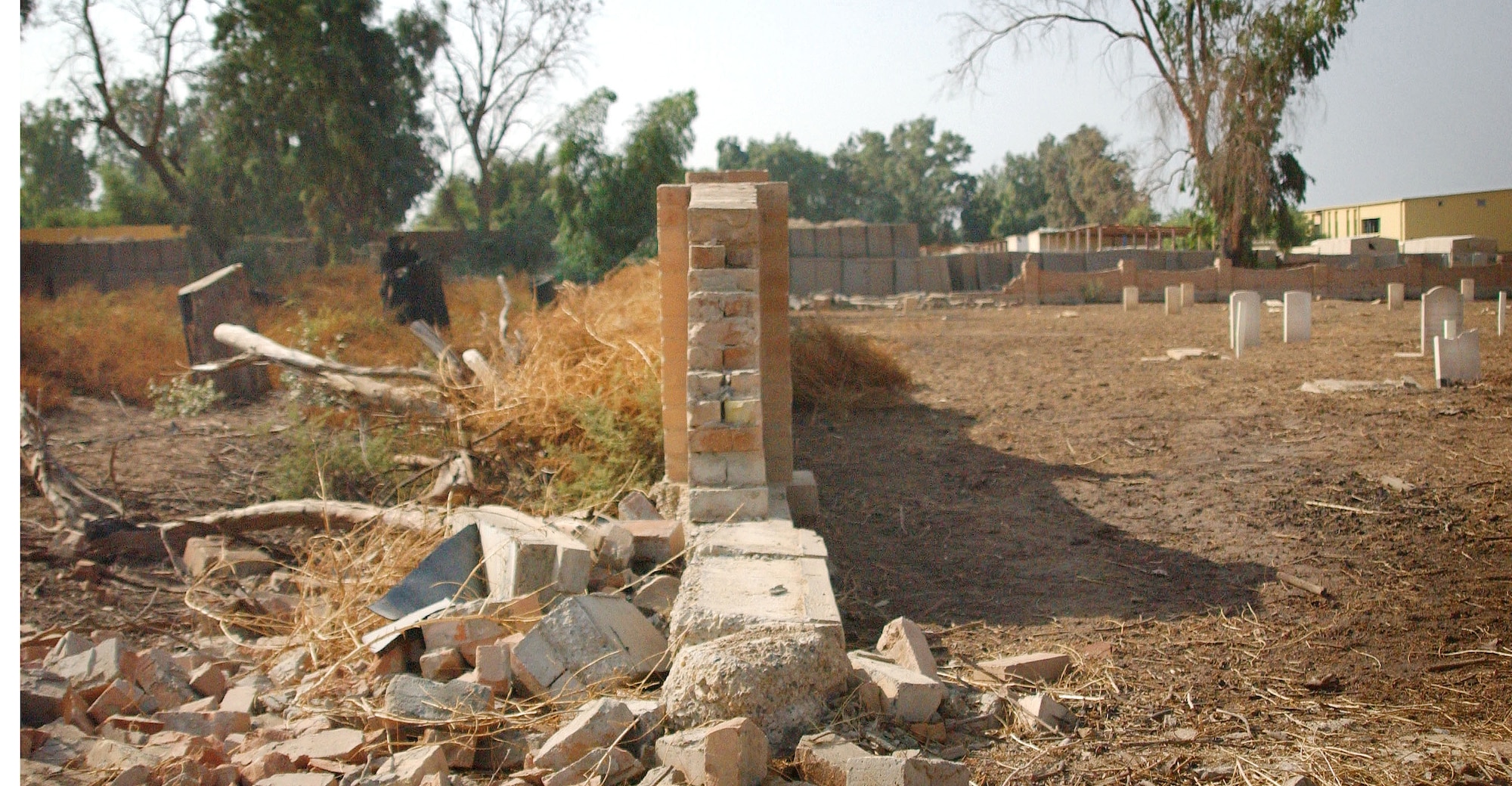 To the right of the wall is a British cemetery located at Camp Habbaniyah, Iraq, as it looks today following the clean-up and maintenance efforts of Camp Habbaniyah personnel, including members of the 732nd Regional Support Unit Habbaniyah. To the left is a similar scene of what the volunteers faced when clean-up work began. (U.S. Air Force Photo/1st Lt. Landon Derentz) 