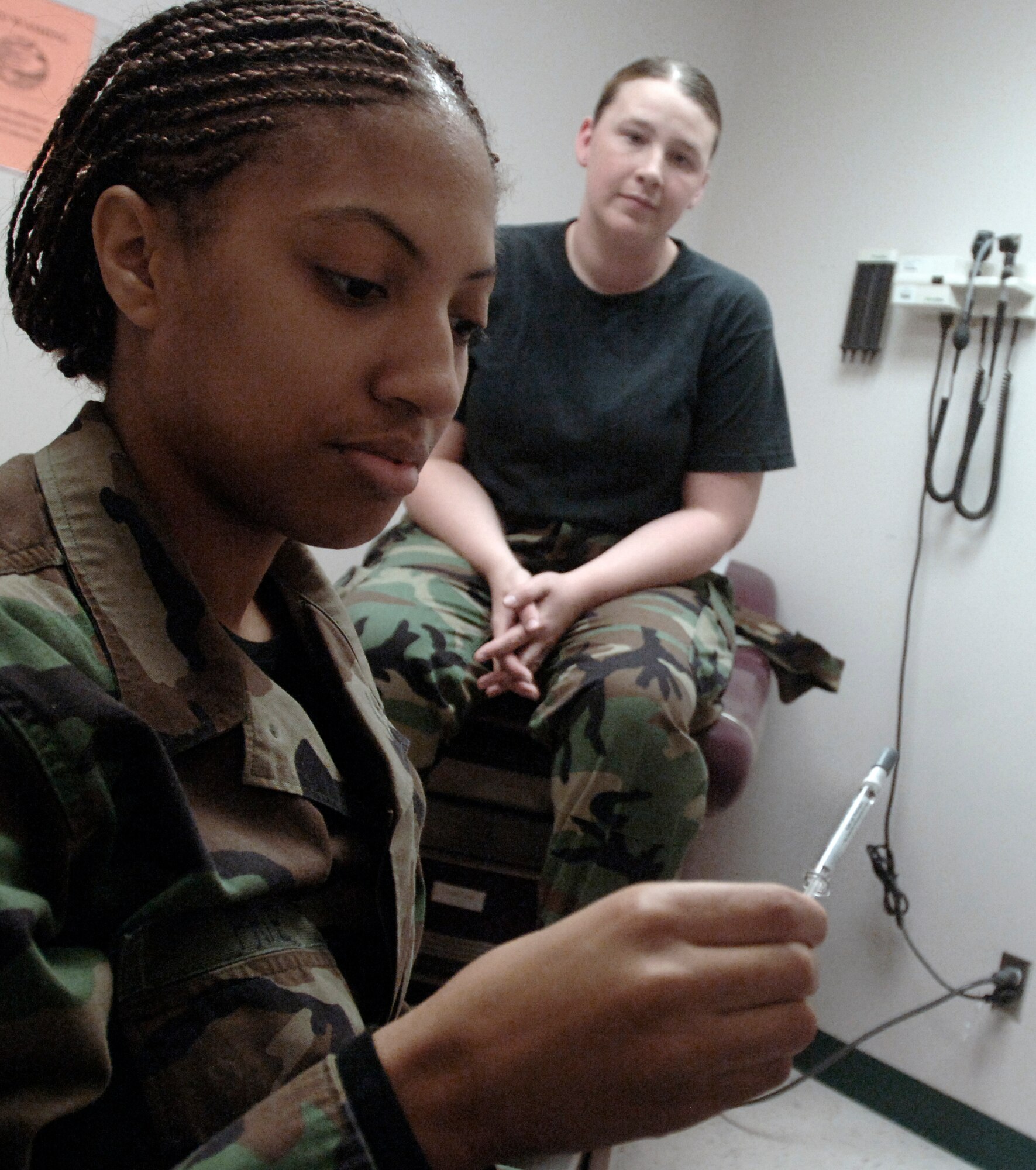 Senior Airman Sherrill Price of the 1st Medical Squadron measures the correct amount of fluid before giving Senior Airman Jessica Friedman on November 28, 2006.   U.S. Air Force photo by Airman 1st Class Vernon Young.