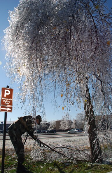 Weather changes--Tech Sgt. Daniel Oliver surveys the damage and does his part to move a damaged tree out of the way.