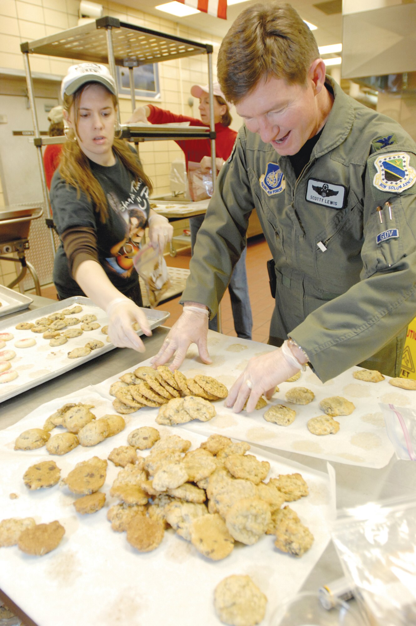 Christina Frey, wife of Capt. Adam Frey, assists Col. Scotty Lewis, 3rd Wing vice commander, as he peels off cookies before they?re packaged for delivery. Volunteers baked cookies as part of the annual cookie caper. The cookies were then delivered by Brig. Gen. Hawk Carlisle, 3rd Wing Commander, Col. Lewis and 3rd Wing Command Chief, Chief Master Sgt. Timothy Carroll.
(U.S. Air Force photo by Tech. Sgt. Keith Brown)