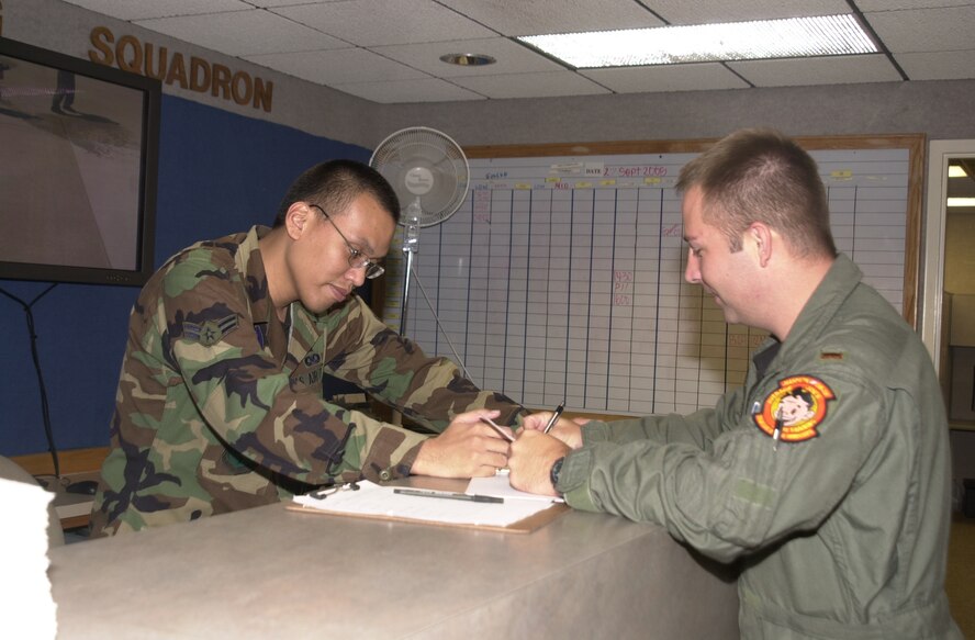 (Photo by Staff Sgt. Amanda Mills) Airman 1st Class Mark Delacruz, 32nd Flying Training Squadron dispatcher, collects fuel receipts from 2nd Lt. Jeremy Keyes, Class 06-05 student, during the last flying hours of fiscal 2005.