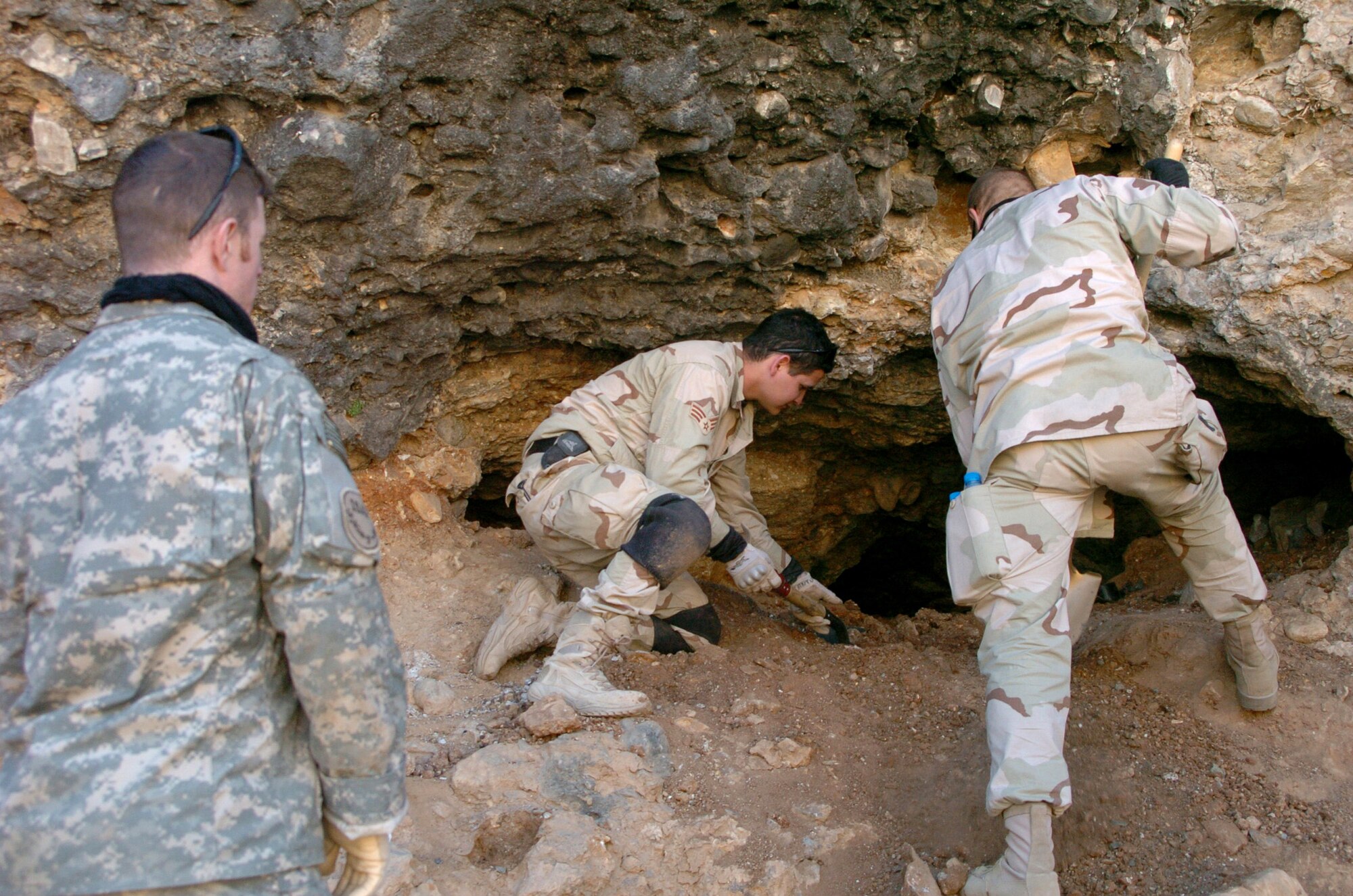 Army Capt. Bradley Miller, left, watches Senior Airman Aaron Cantu and Maj. Shawn Murphy dig inside a cave in search of suspected weapons caches Nov. 25 in Landikheyl, Afghanistan. Captain Miller is assigned to Task Force Gauntlet, 10th Mountain Division, and Airman Cantu and Major Murphy are from Explosive Ordnance Disposal/Operating Location A, attached to 63rd Ordnance Battalion. (U.S. Army photo/Cpl. Bertha A. Flores)
