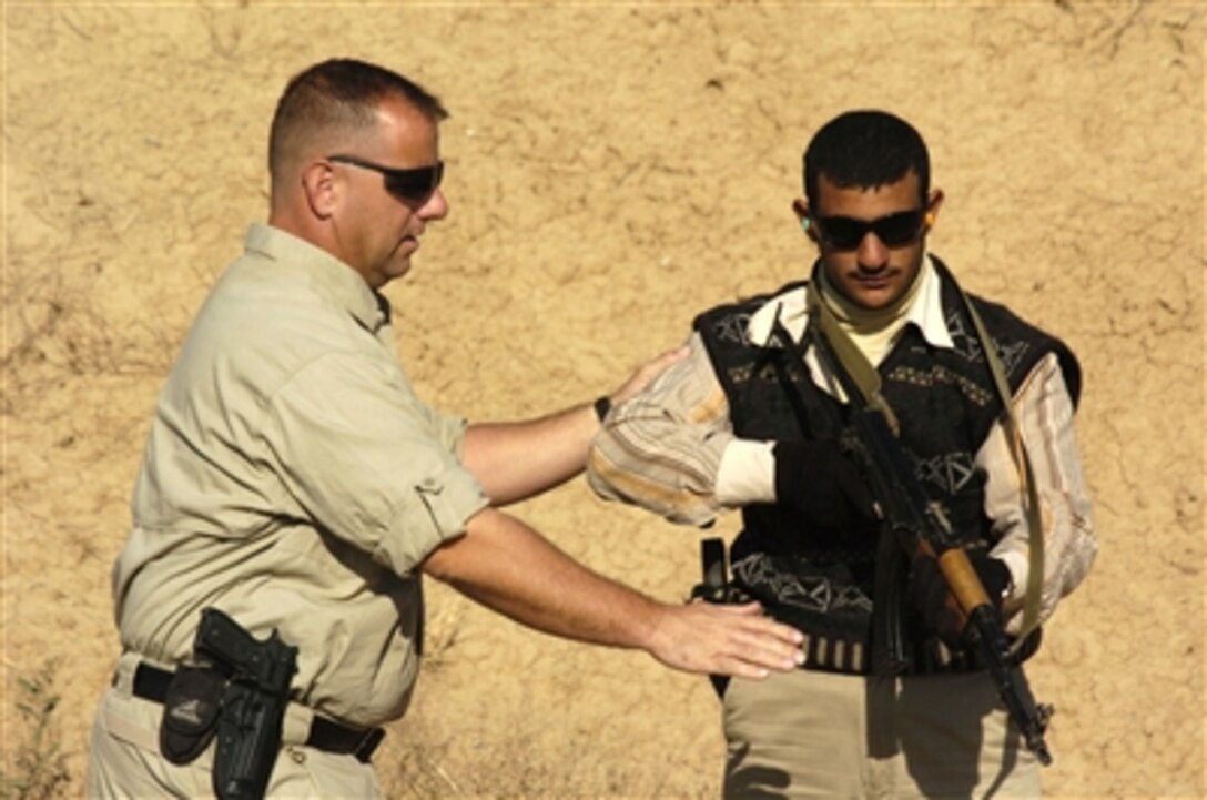 Mark Armstrong (left), a Department of Defense police officer with the International Police Liaison Office, teaches an Iraqi policeman the low-ready weapon position during Special Weapons And Tactics training at a range on Forward Operating Base McHenry, Iraq, on Nov. 30, 2006.  Police officers from the Liaison Office and U.S. Army soldiers from the 2nd Battalion, 300th Field Artillery Brigade are conducting the SWAT training.  