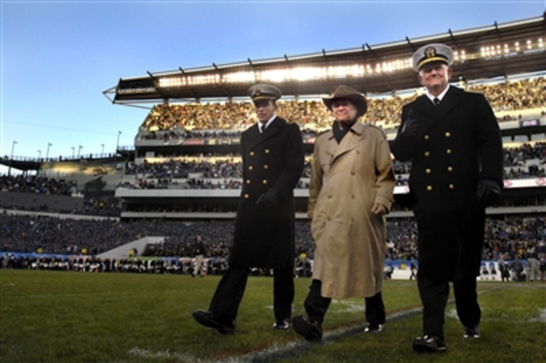 Superintendent of the United States Naval Academy Vice Adm. Rodney Rempt, right, and a Naval Academy senior midshipman escort Defense Secretary Donald H. Rumsfeld across the field to watch the second half of the Army-Navy game from the Navy side in Philadelphia, Dec. 2, 2006. 