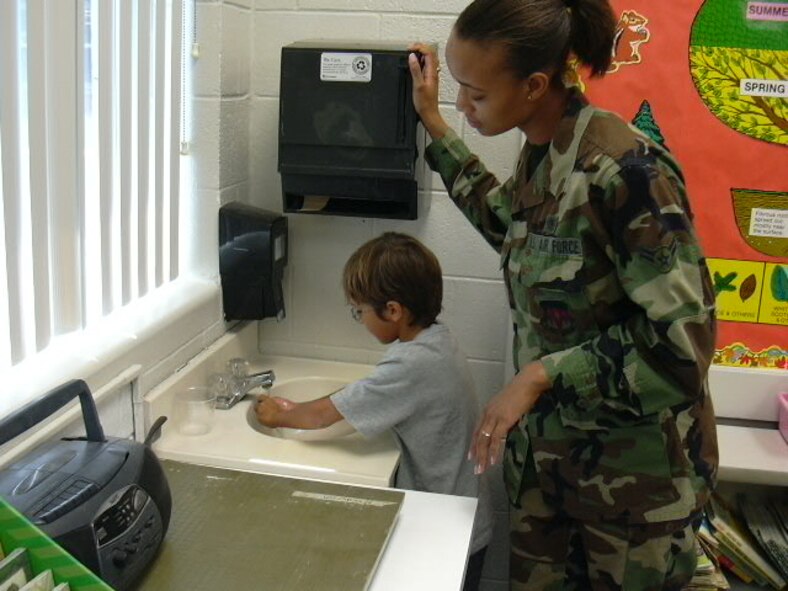 (Photo by 2nd Lt. Kasey Jackson) Airman 1st Class Savannah Key, 71st Medical Operations Squadron, instructs an Eisenhower Elementary School student on proper hand washing techniques. 