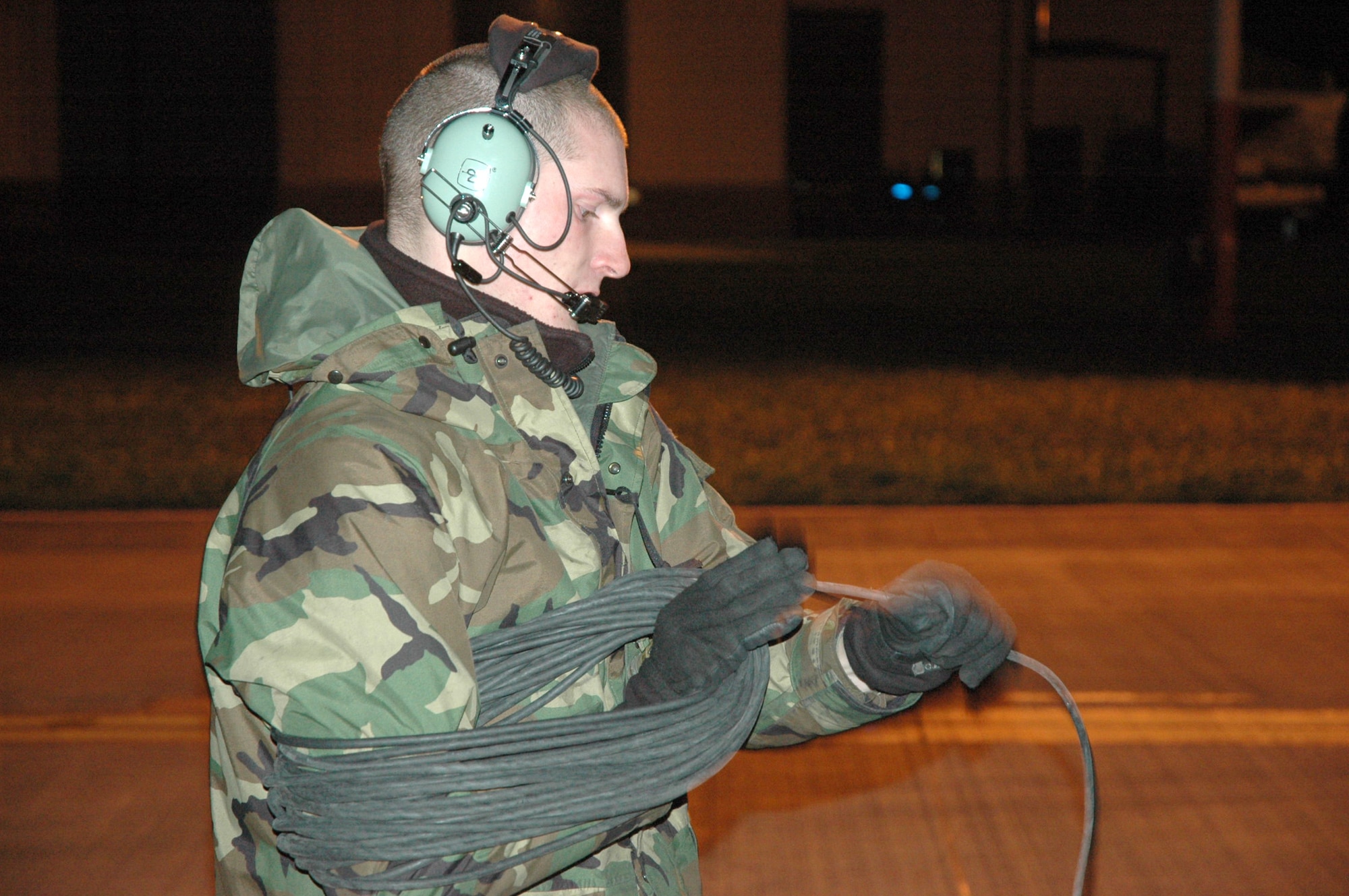 Staff Sgt. Justin Elder rolls up a communications line following an engine run-up and defueling at Royal Air Force Mildenhall, England, Dec. 4. KC-135 Stratotanker aircrews, crew chiefs and maintainers from Fairchild Air Force Base, Wash., and Grand Forks AFB, N.D., are deployed RAF Mildenhall to augment its refueling wing. Sergeant Elder is a crew chief assigned to the 92nd Air Refueling Wing. (U.S. Air Force photo/Tech. Sgt. Scott Wakefield)