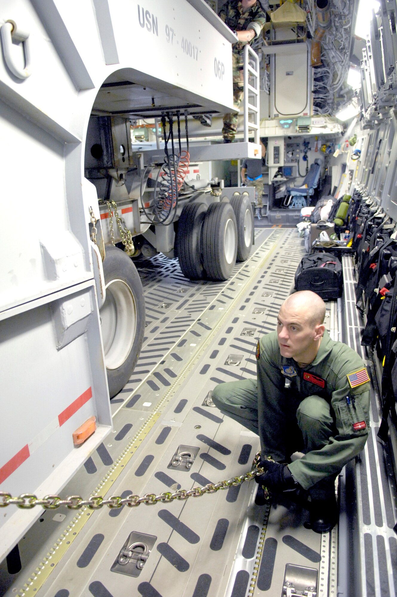 Airman 1st Class Paul Trowbridge secures a dry dock transport vehicle to the floor of a C-17 Globemaster III Dec. 2 at Hickam Air Force Base, Hawaii. The flight was the first operational movement of a dry dock transport by a C-17. Airman Trowbridge is a loadmaster assigned to the 535th Airlift Squadron. (U.S. Air Force photo/Tech. Sgt. Shane A. Cuomo)
