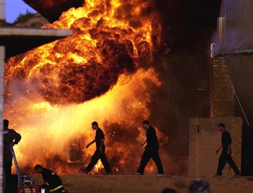 Iraqi fire fighters attempt to keep a blaze under control following a rocket attack on a pipeline feeding a 10,000 liter holding tank at the Northern Oil Company in Kirkuk, Iraq, Nov. 27, 2006.