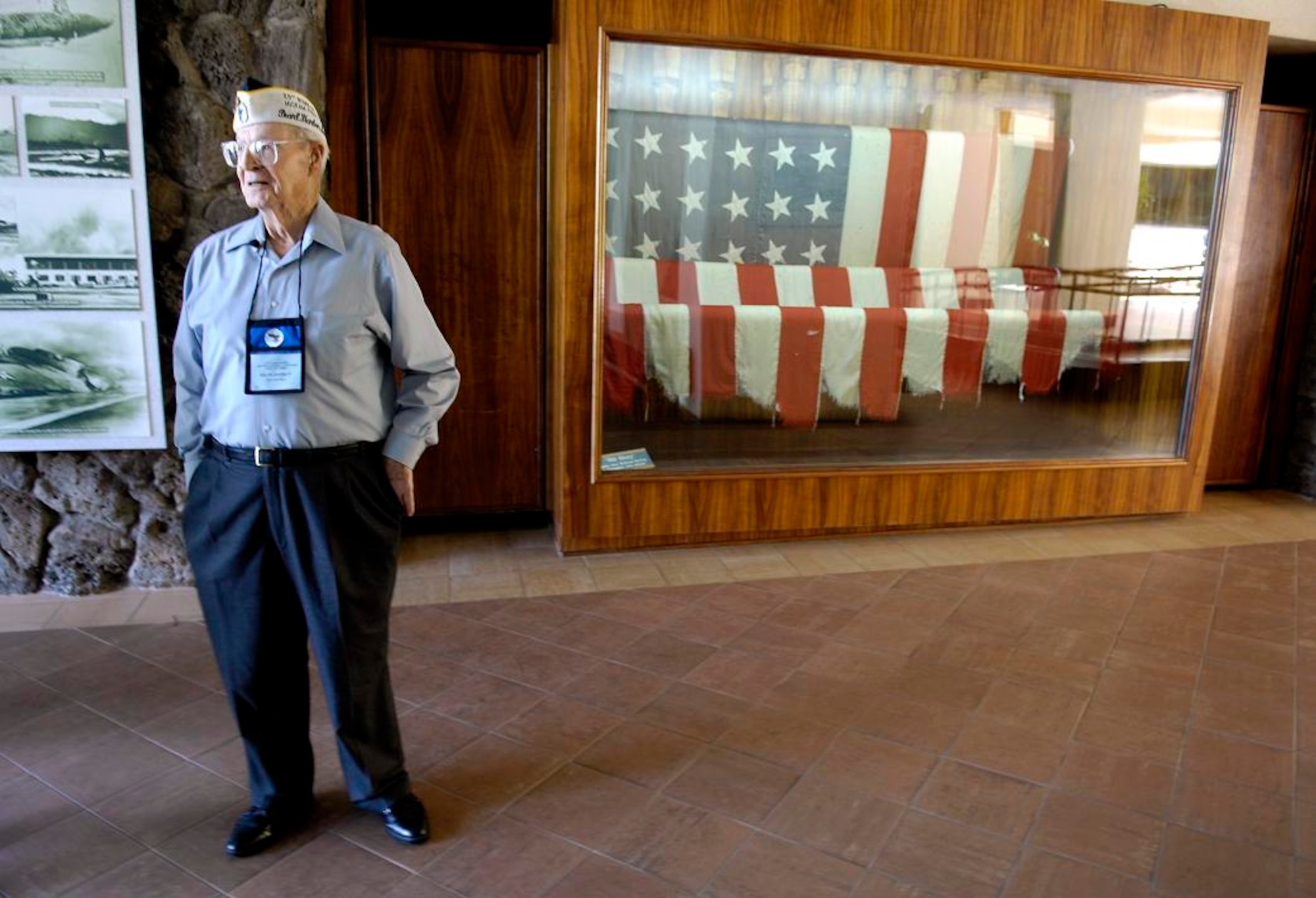 Retired Chief Master Sgt. Ralph Barnett stands in the foyer of the Pacific Air Forces Headquarters building Dec. 4 at Hickam Air Force Base, Hawaii. The flag that Chief Barnett is standing in front of was the flag that flew over Hickam Field during the attack on Dec. 7, 1941.  (U.S. Air Force photo/ Tech. Sgt. Shane A. Cuomo)
