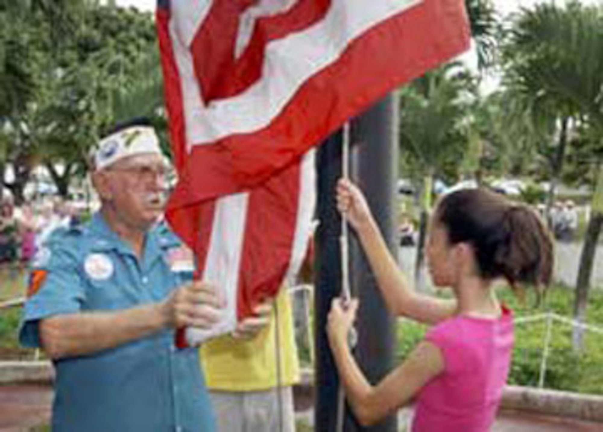 Retired Master Sgt. Richard Fiske receives a helping hand from Erica Solomon in raising the colors at the USS Arizona Memorial visitor center in Honolulu, Hawaii, in 2001. The Pearl Harbor survivor volunteered at the center as a goodwill ambassador for more than 20 years.  (Courtesy photo)