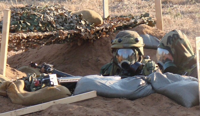 (Photo by 2nd Lt. James Justice) Vance Airmen in Mission Oriented Protective Posture equipmen occupy a defensive fighting position at Kegelman Auxiliary Field as part of the Combat Readiness Course held Nov. 14 to 17. MOPPis used to protect members from known chemical and biological agents.