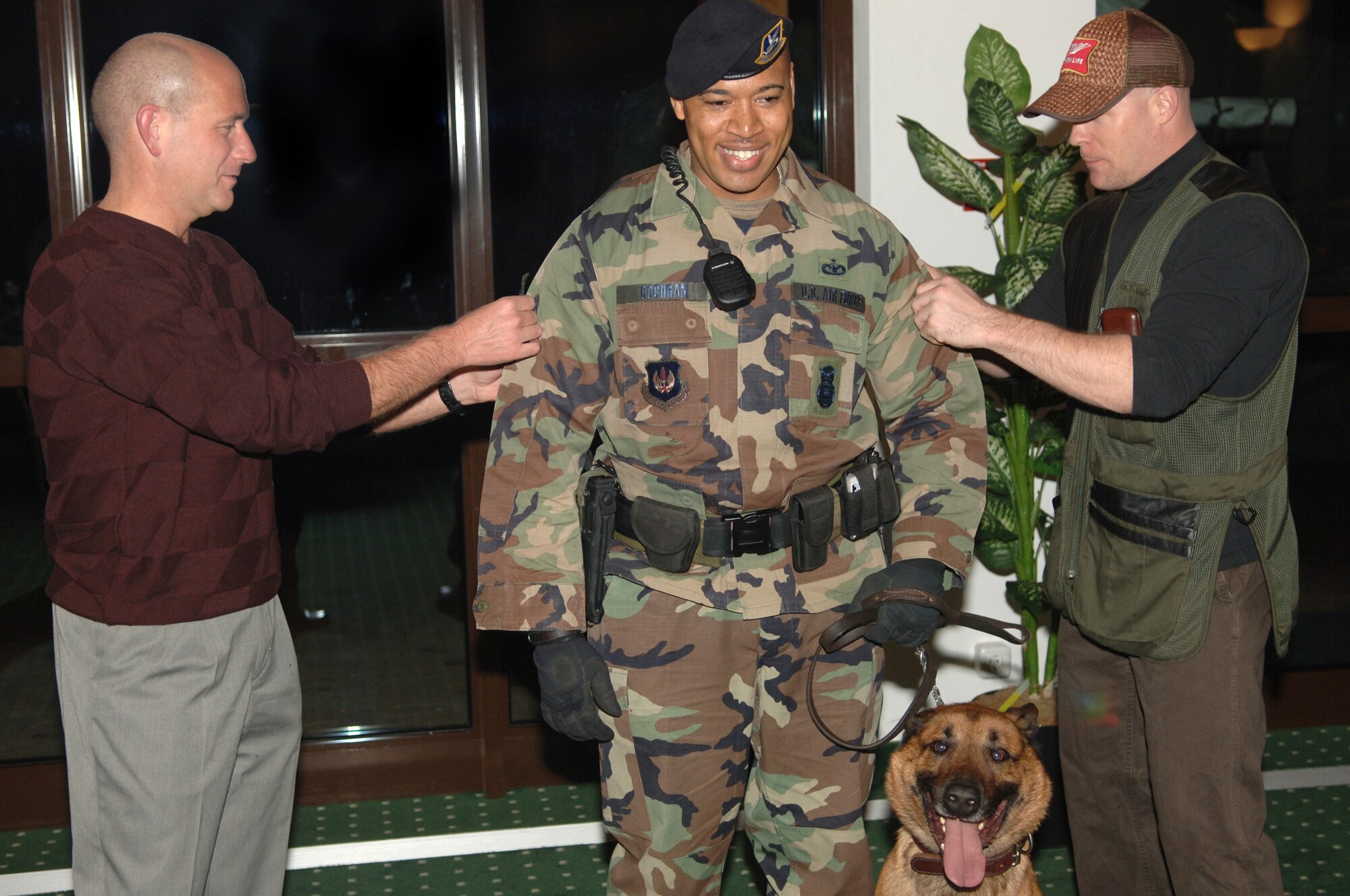 Col Kurt Lohide, 435th Air Base Wing Commander, left and Maj Ron Gray, 435th Security Forces Squadron Commander promoted Staff Sgt. Rodney Cochran to technical sergeant. Cochran, who got picked up in the supplemental board, arrived with his military working dog Boyke, to do a routine sweep of the building and unaware he was to be promoted.  

